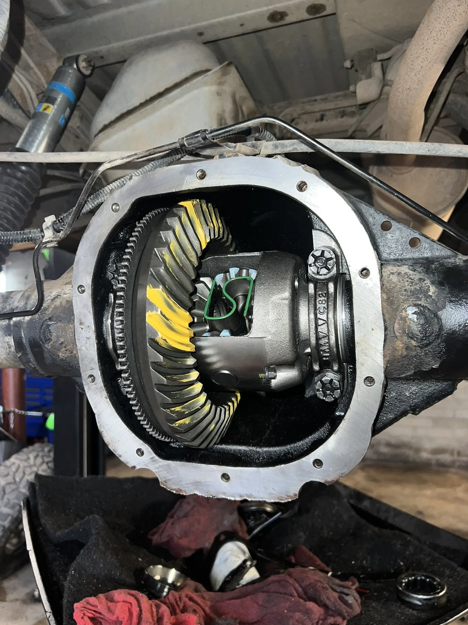 A partially disassembled automotive differential, showing the internal gears and components, with a wrench and rag in a workshop setting.