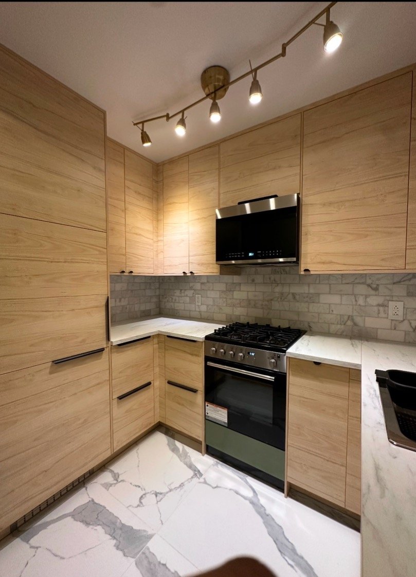 A modern kitchen with light wood cabinets, a marble countertop, licensed Insured Bonded home improvement contractor in New Jersey