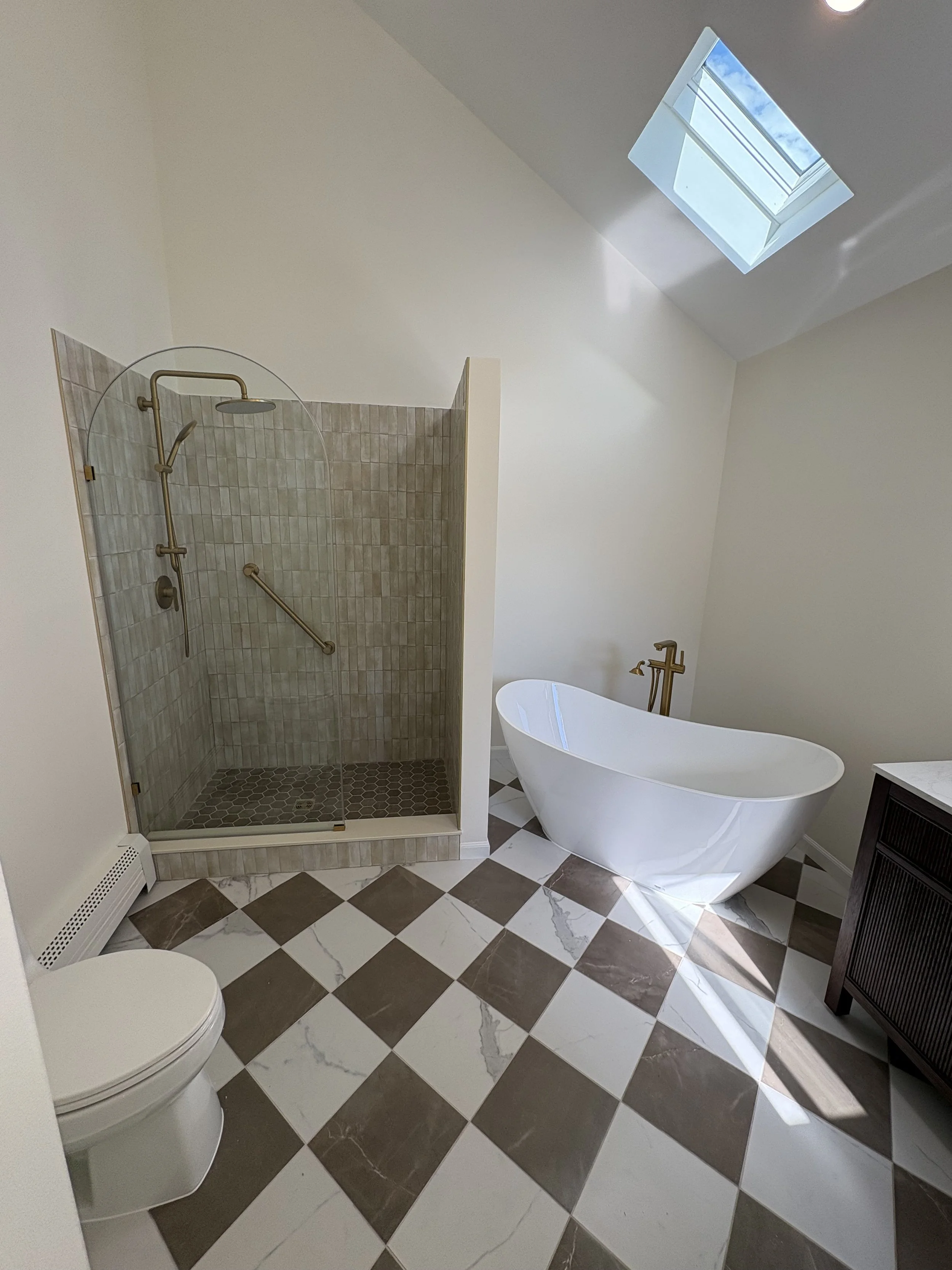 A bathroom with a shower stall, a freestanding bathtub, a toilet, and a dark wood cabinet. licensed Insured Bonded home improvement contractor in New Jersey