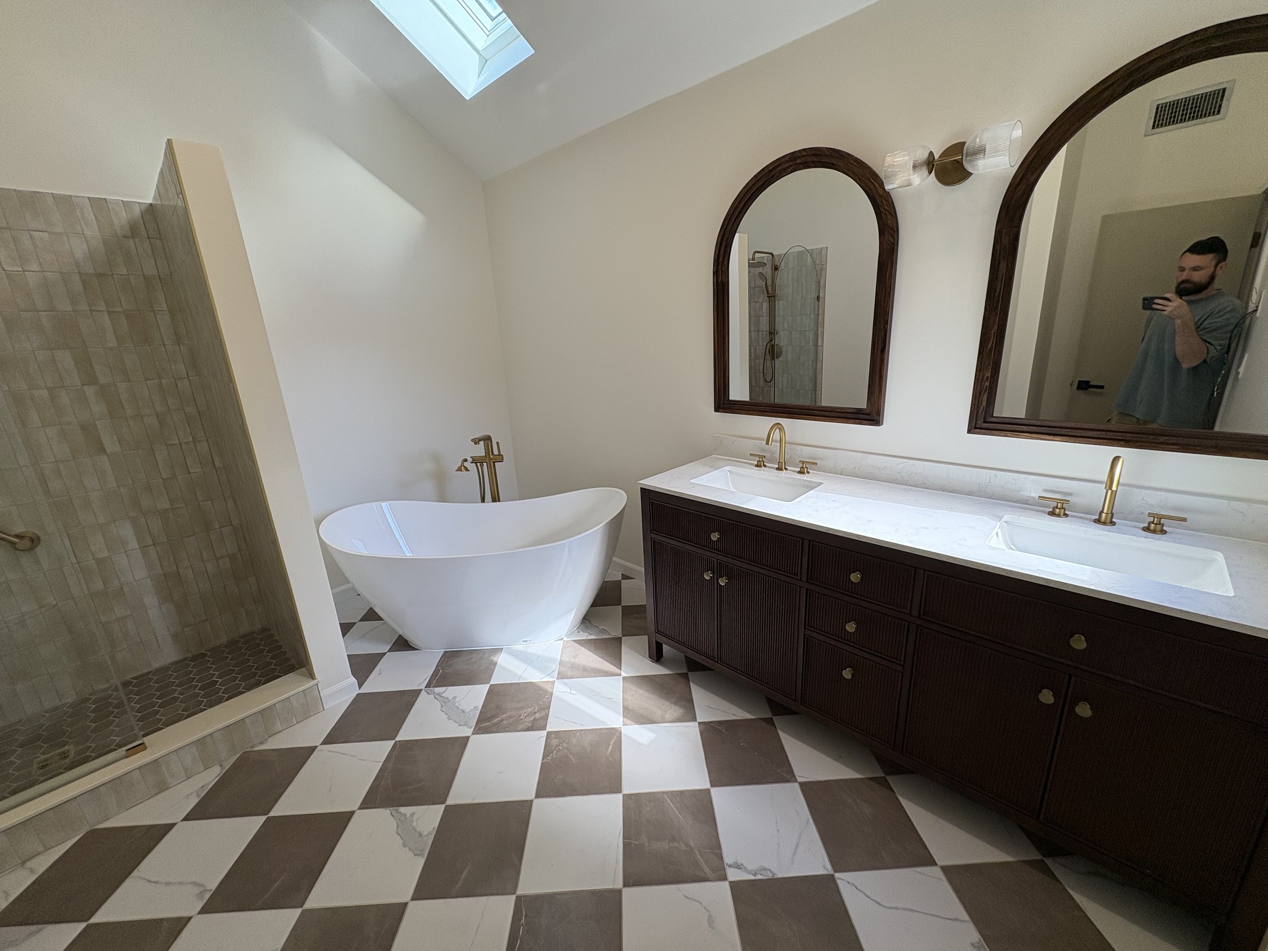  bathroom renovation with a hanging shower, a dark wood vanity with two sinks and gold fixtures, two large mirrors licensed Insured Bonded home improvement contractor in New Jersey