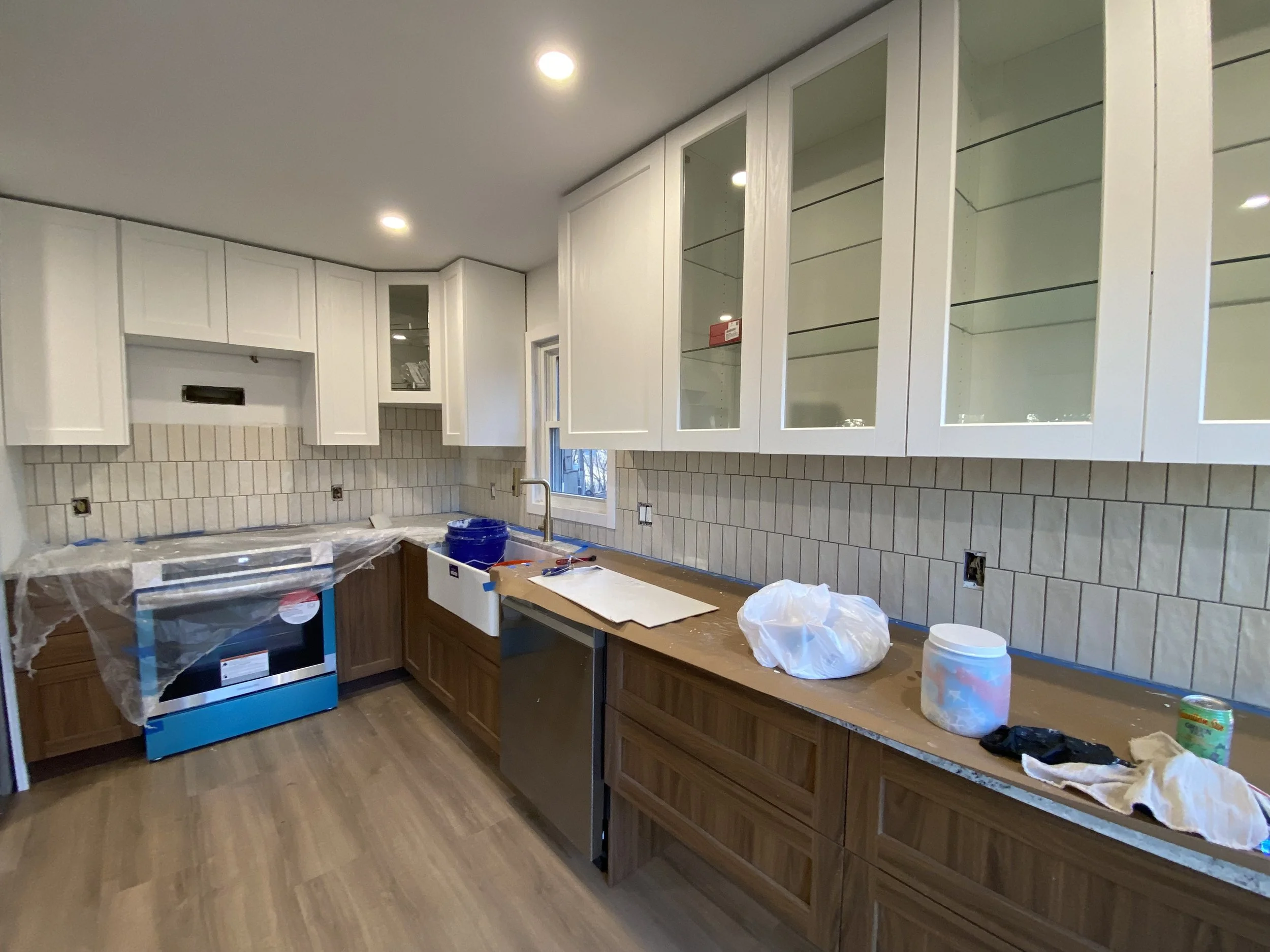 Kitchen under renovation with white cabinets, a window, and construction supplies on the countertop licensed Insured Bonded home improvement contractor in New Jersey design and build installation