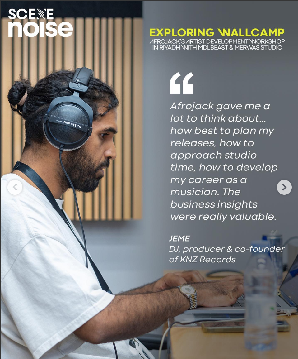 A man with dark hair tied back and a beard wearing headphones and a white shirt, working on a laptop in a studio setting with a water bottle on the table. There is a background with vertical wooden slats and a quote from Jeme, a DJ and co-founder of KNZ Records, overlayed on the right side.