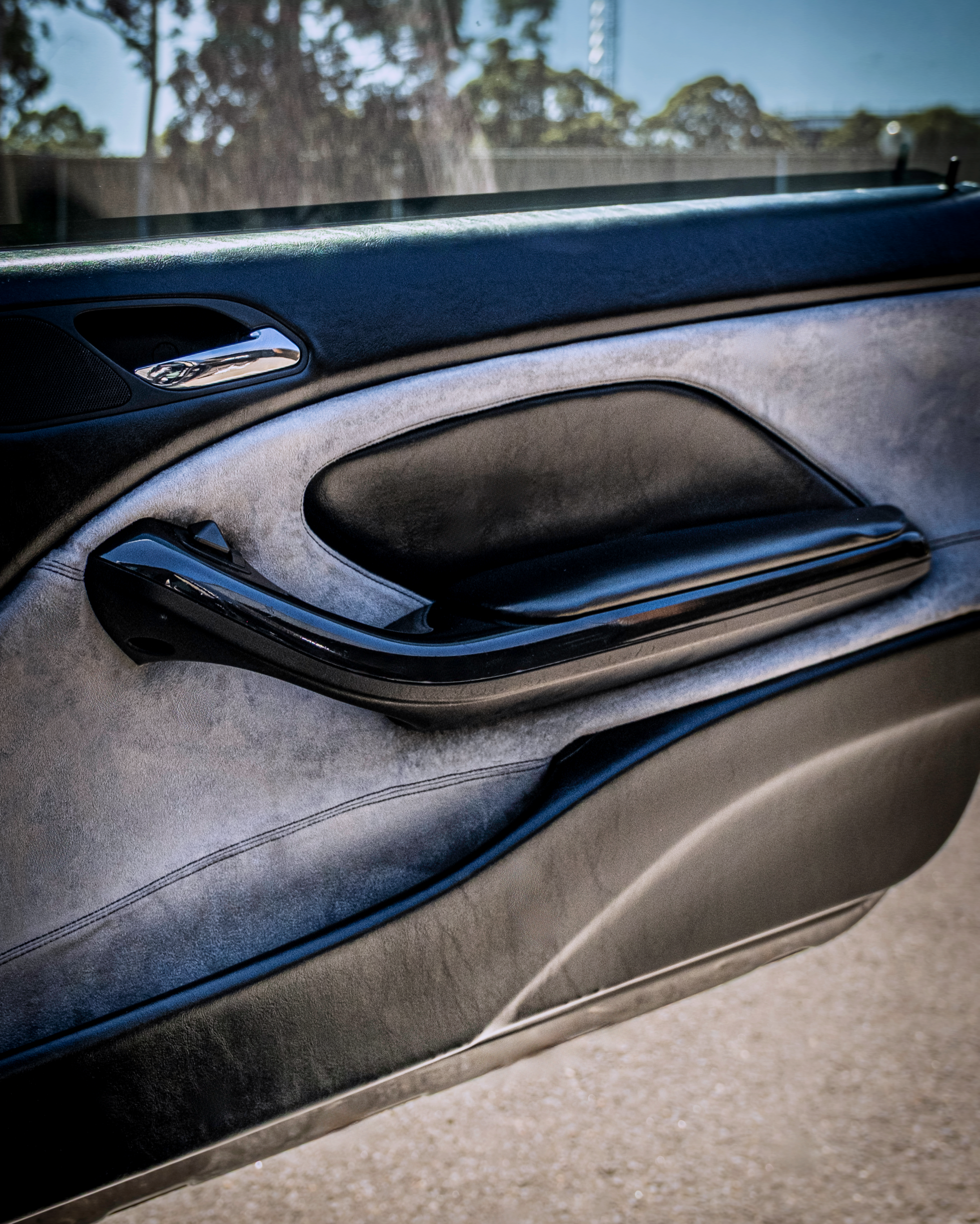 Bespoke car door card upholstery and retrim by Visions Customs Castle Hill. Detailed view of a premium interior restoration featuring custom grey suede door panels, black vinyl armrests, and precise stitching.