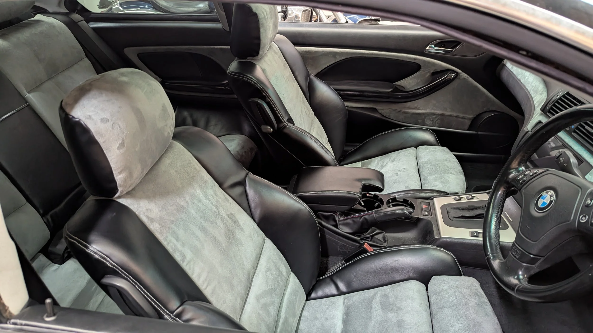 Complete BMW interior custom auto upholstery retrim by Visions Customs Castle Hill. Full cabin restoration featuring black vinyl bolsters and grey suede center inserts on front seats, rear seats, and door cards.