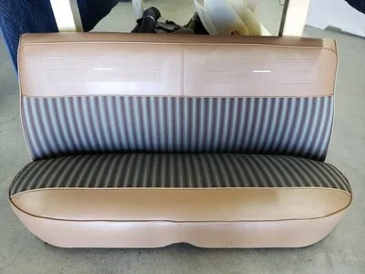 An upholstered vintage bench with a striped OEM fabric and tan vinyl 