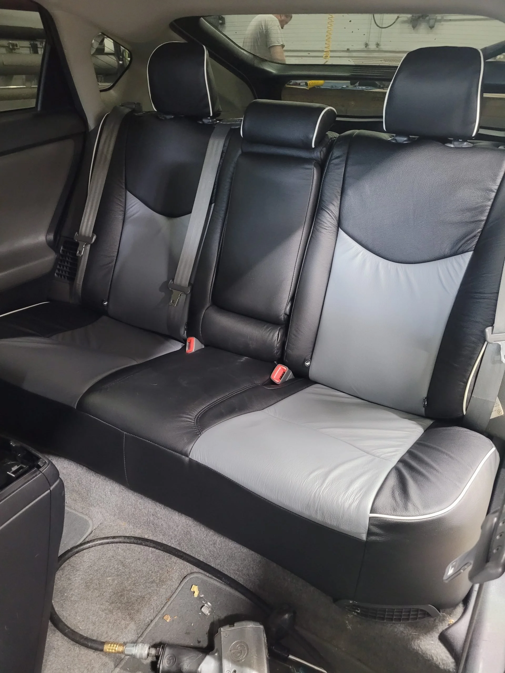The interior of a vehicle showing the back seat area with black and gray Katzkin Leather seats and headrests. 