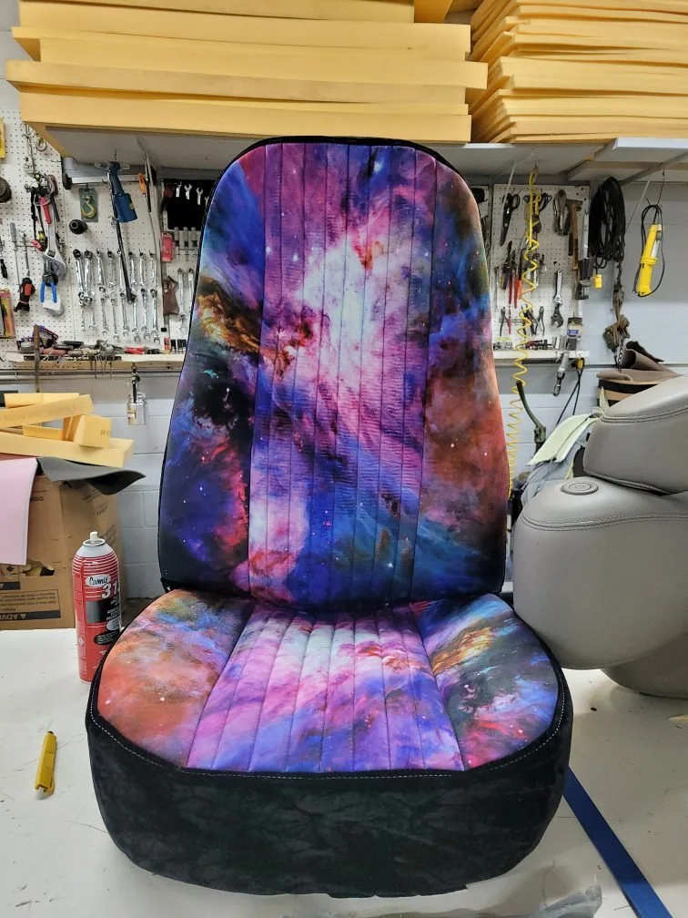A car seat with galaxy print fabric, featuring nebulae and stars.