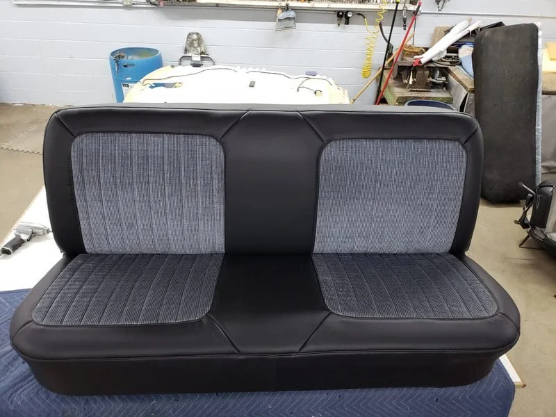 A black and gray two-tone bench seat. Vinyl wrap with cloth inserts.