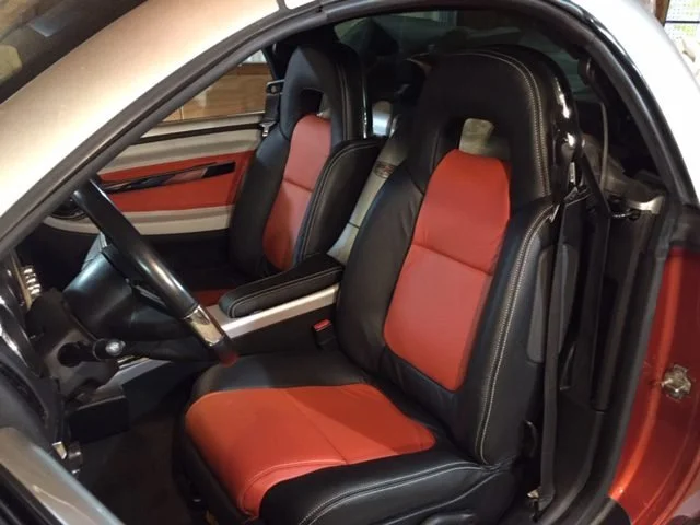 Interior of a car showing front seats with black and orange upholstery. Katzkin Leather Kit.