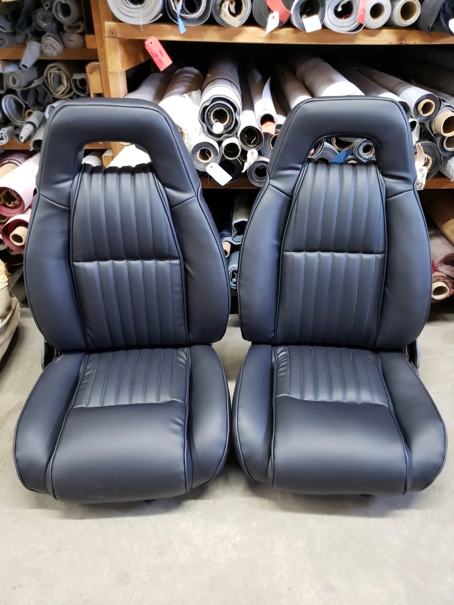 Two black car bucket seats with vertical stitching.
