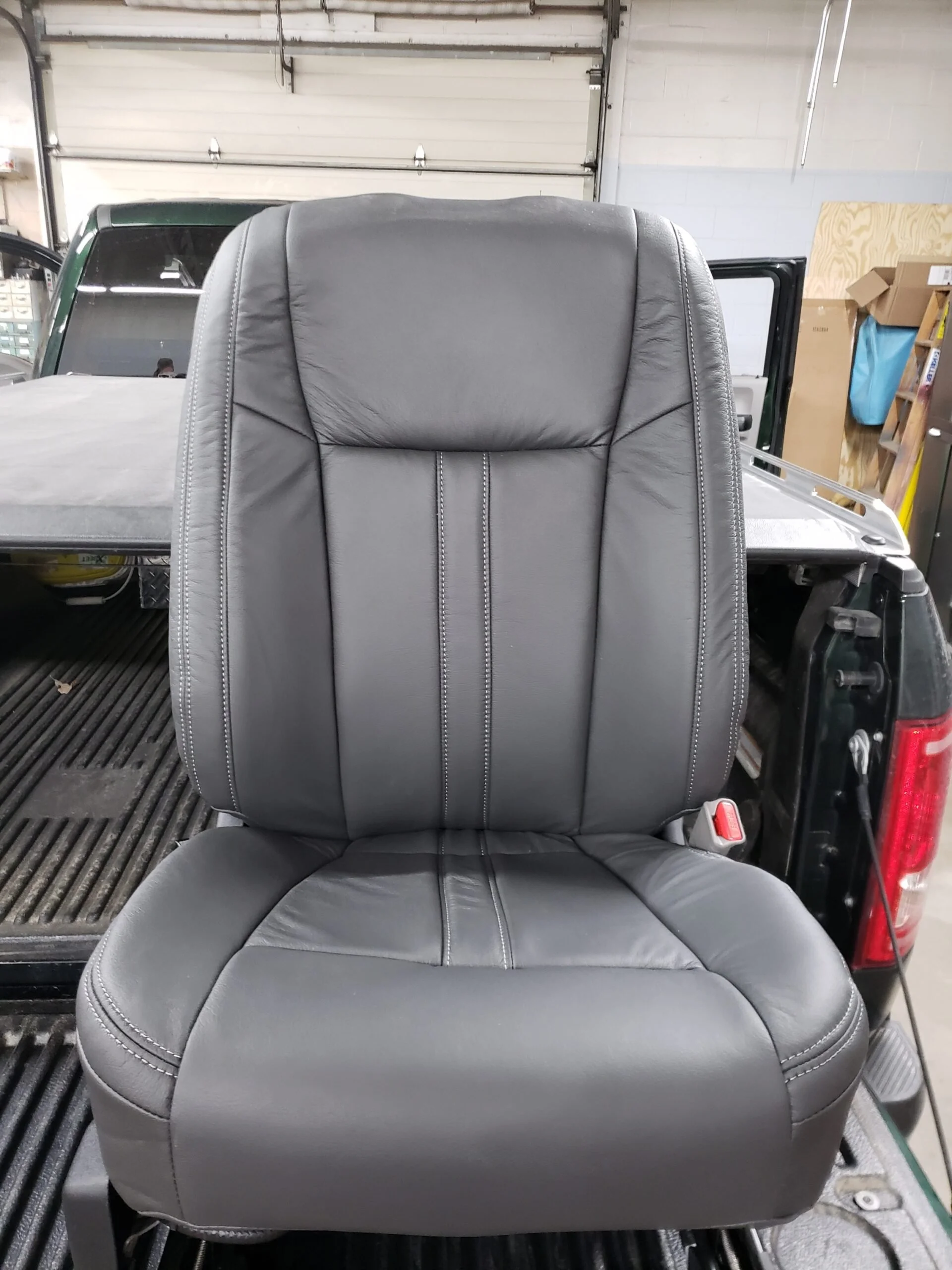 The image shows a close-up view of a black leather car seat with contrast stitch, Katzkin Leather Kit.