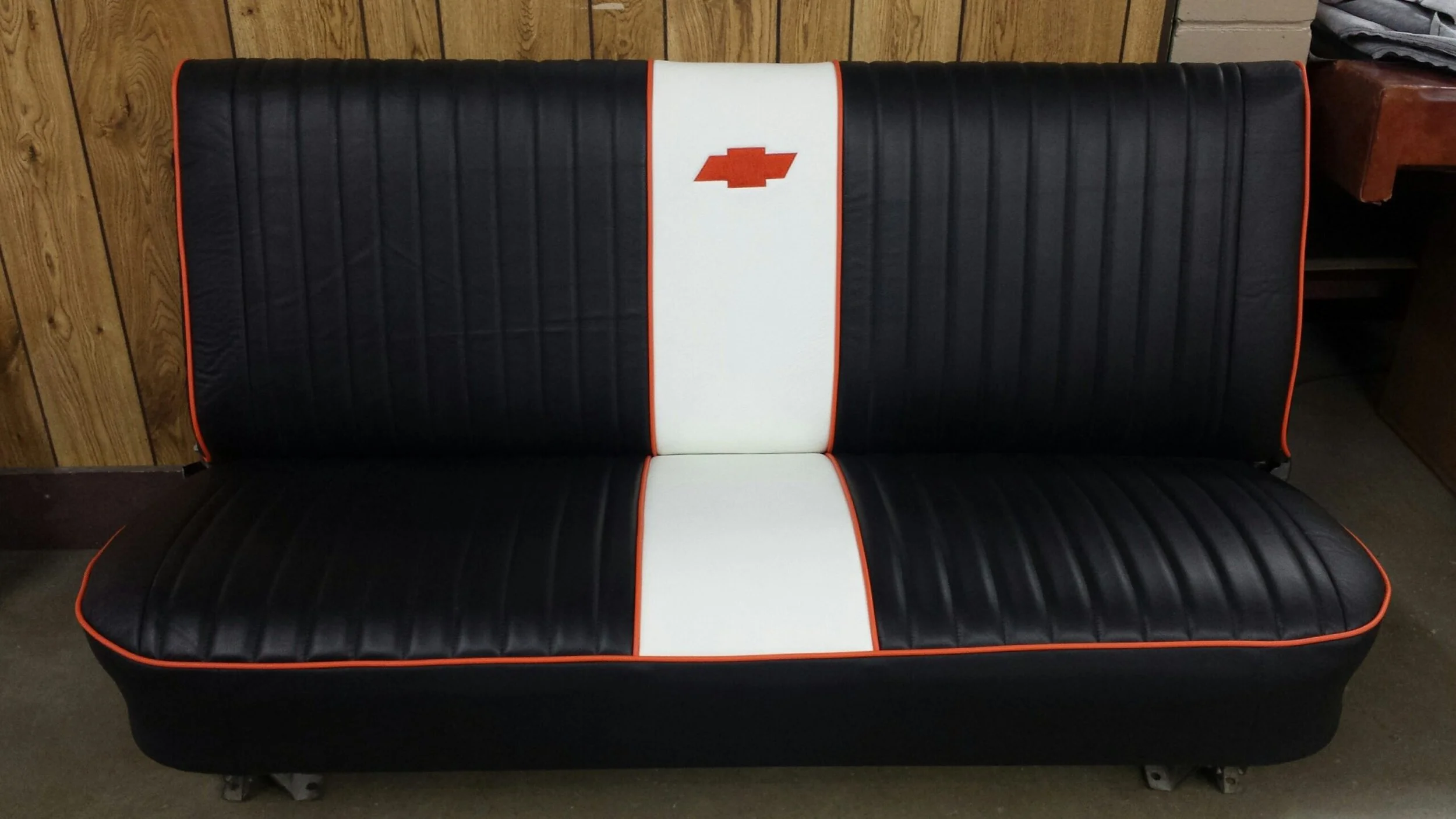 Black vintage bench with red beading and a white stripe with a red Chevrolet emblem in the center