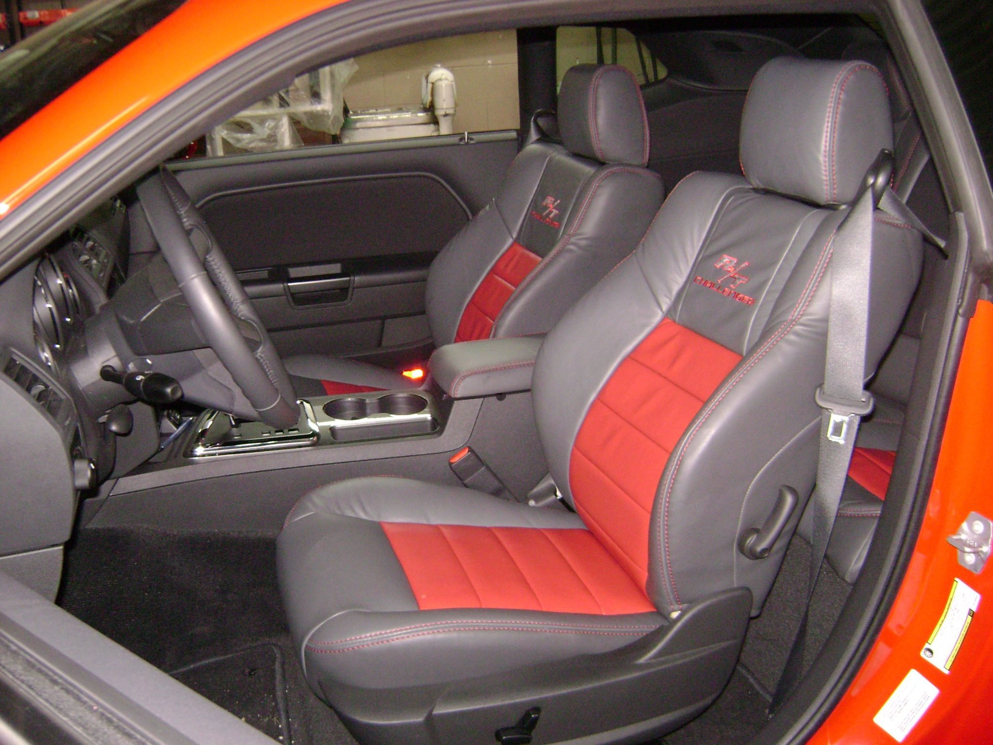 The interior of Challenger, two front bucket seats with black leather upholstery accented by red stitching and the 'HHR Challenger' logo embroidered on the headrests. Katzkin Leather Kit.