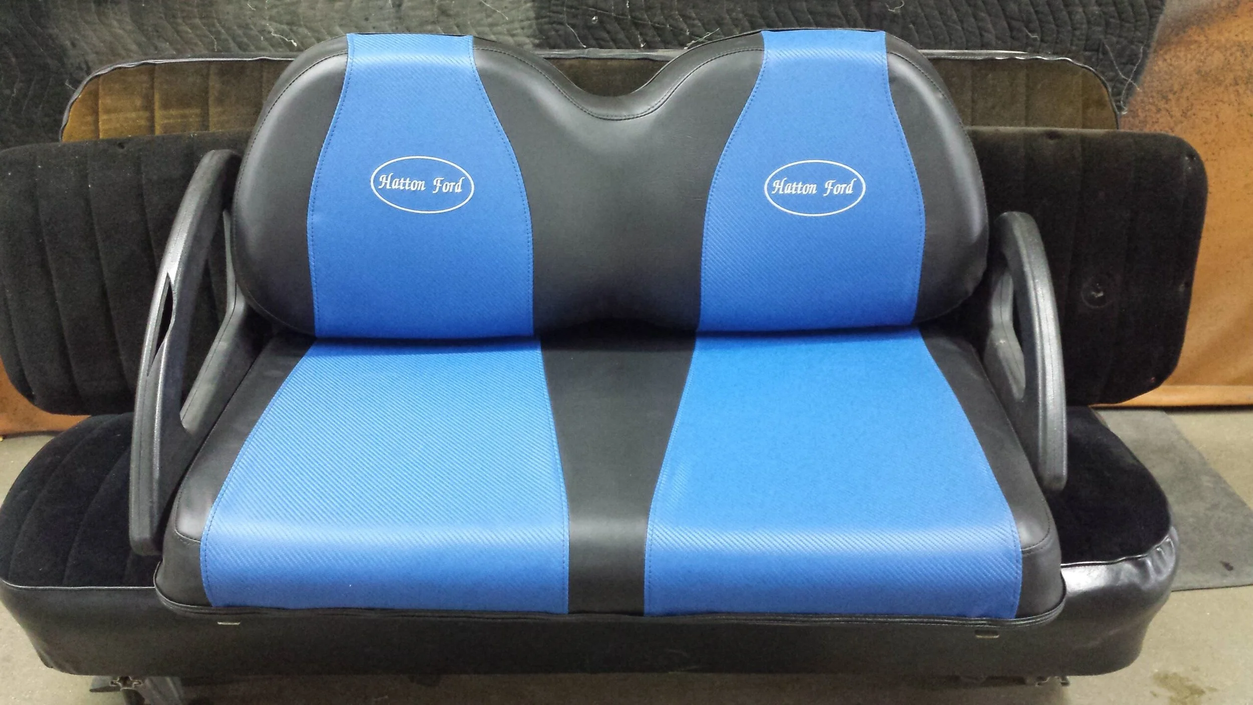 A blue carbon fiber and black golf cart seat with embroidery