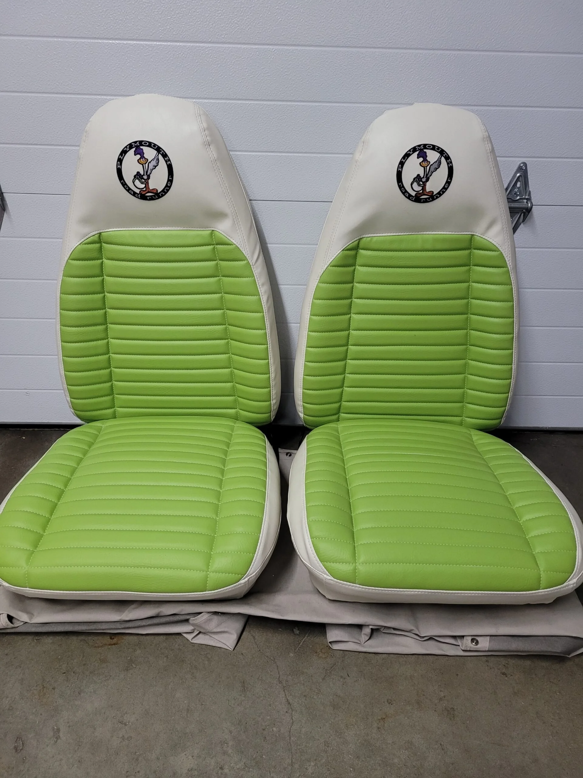 Pair of green and white bucket seats with a logo featuring a purple bird.