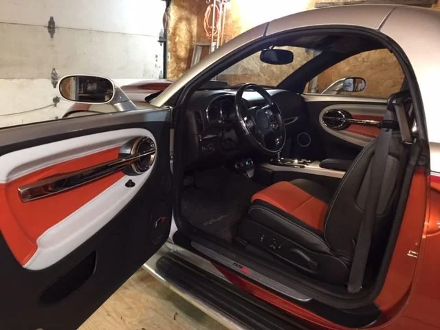 The interior of a modern sports car with orange, black, and white accents...Katzkin Leather Kit.