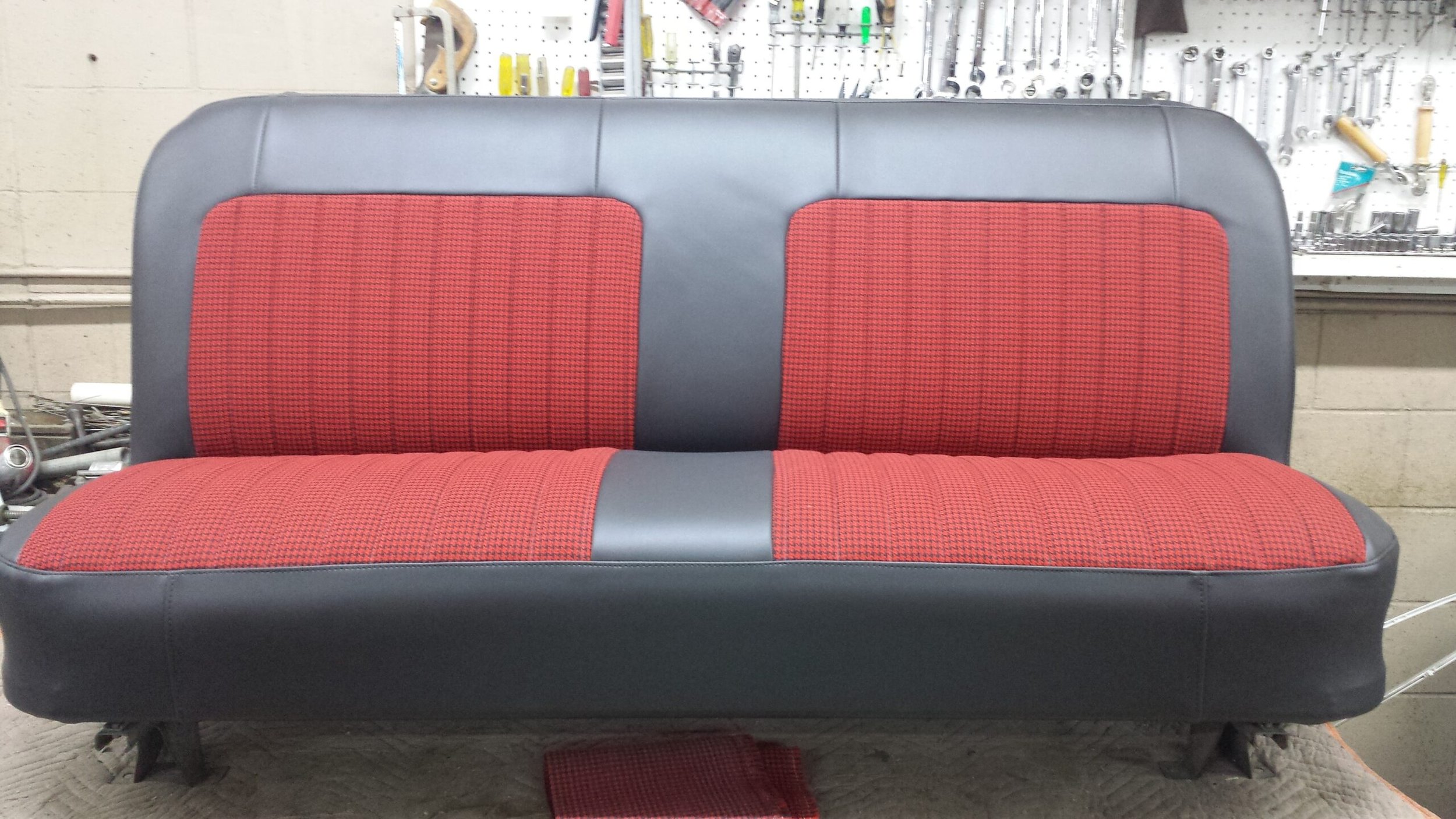 A vintage automotive bench seat with red and black upholstery