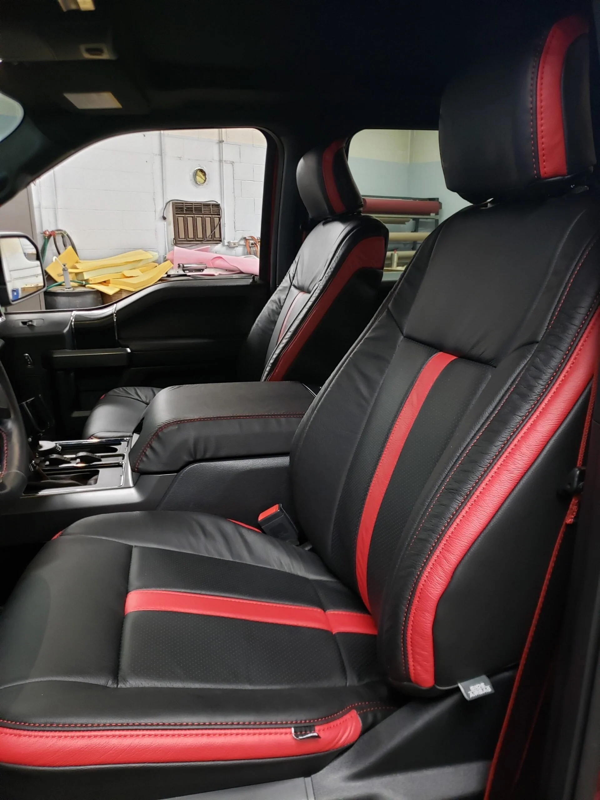 The image shows the interior of a vehicle, focusing on the front passenger and driver seats which are Katzkin Leather, black with red accents. 