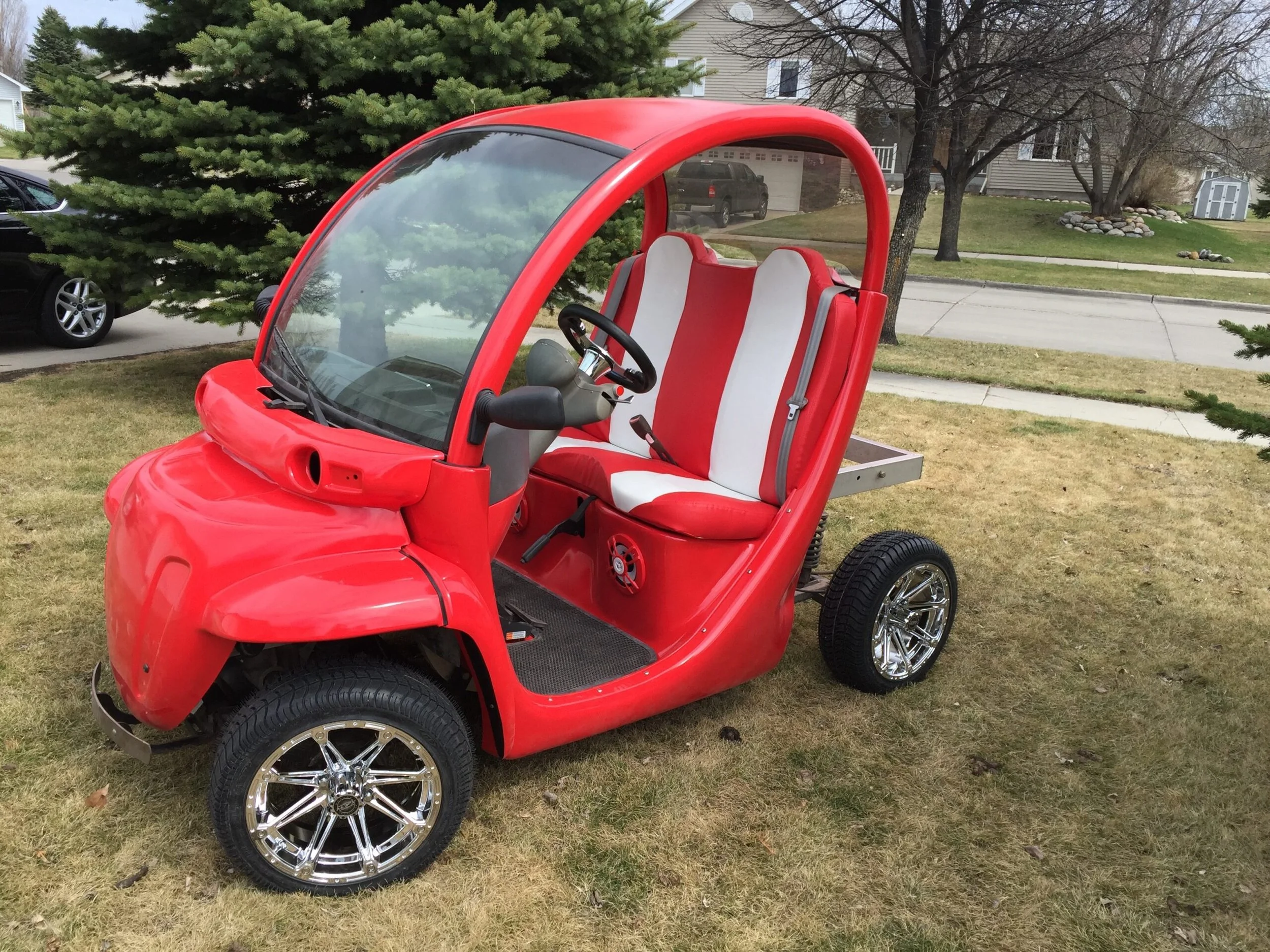 A small red electric golf cart with white and red seats