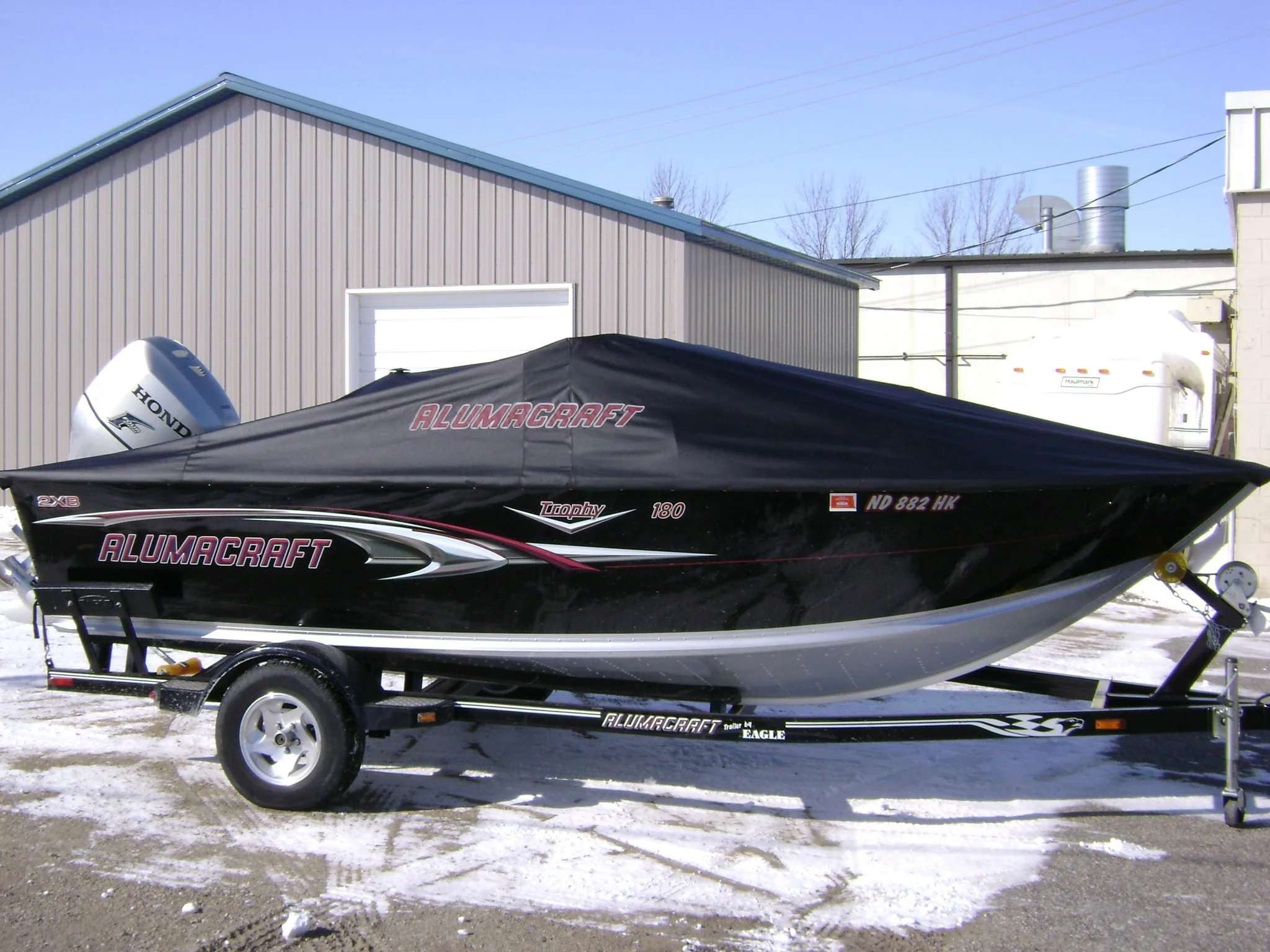 A small aluminum boat w 'AlumaCraft' on custom boat cover