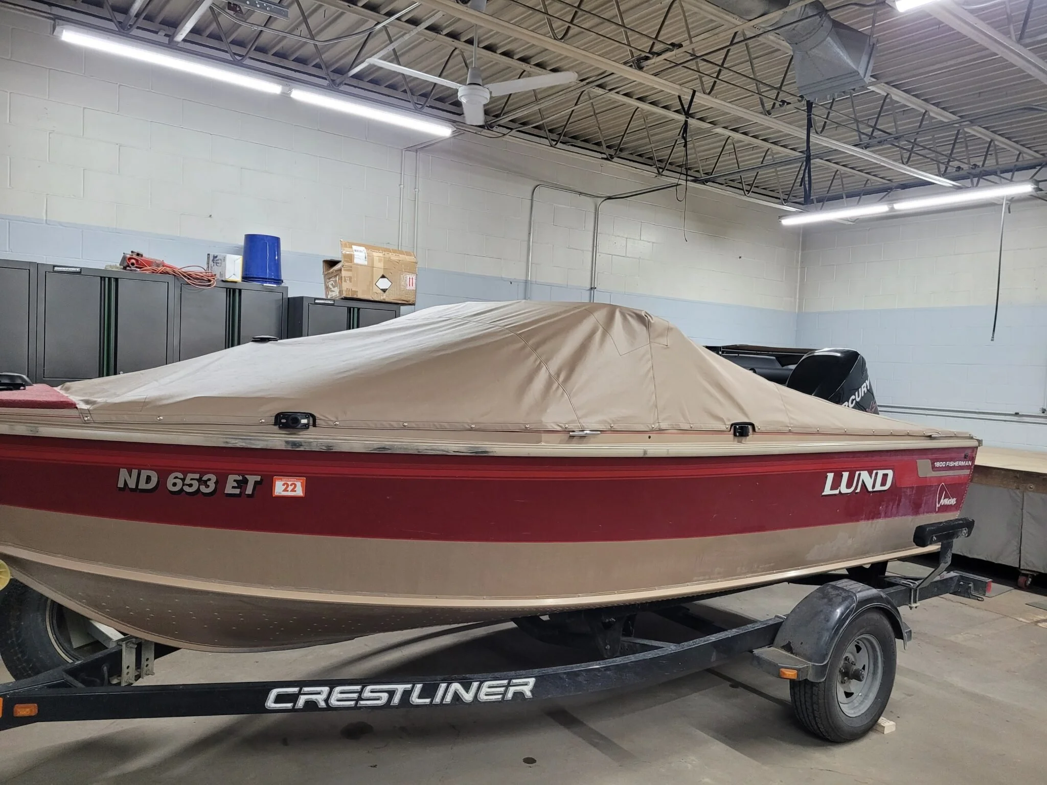 A red Lund boat with a beige custom cover on a trailer