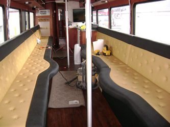 Inside of a Limo bus with black and tan upholstered seats.