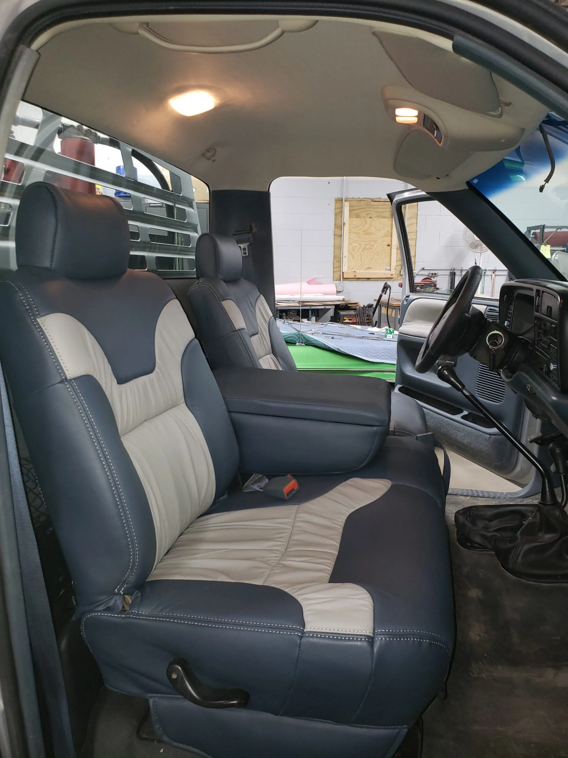The interior of a vehicle showing black and beige upholstered front seats, Katzkin Leather Kit.