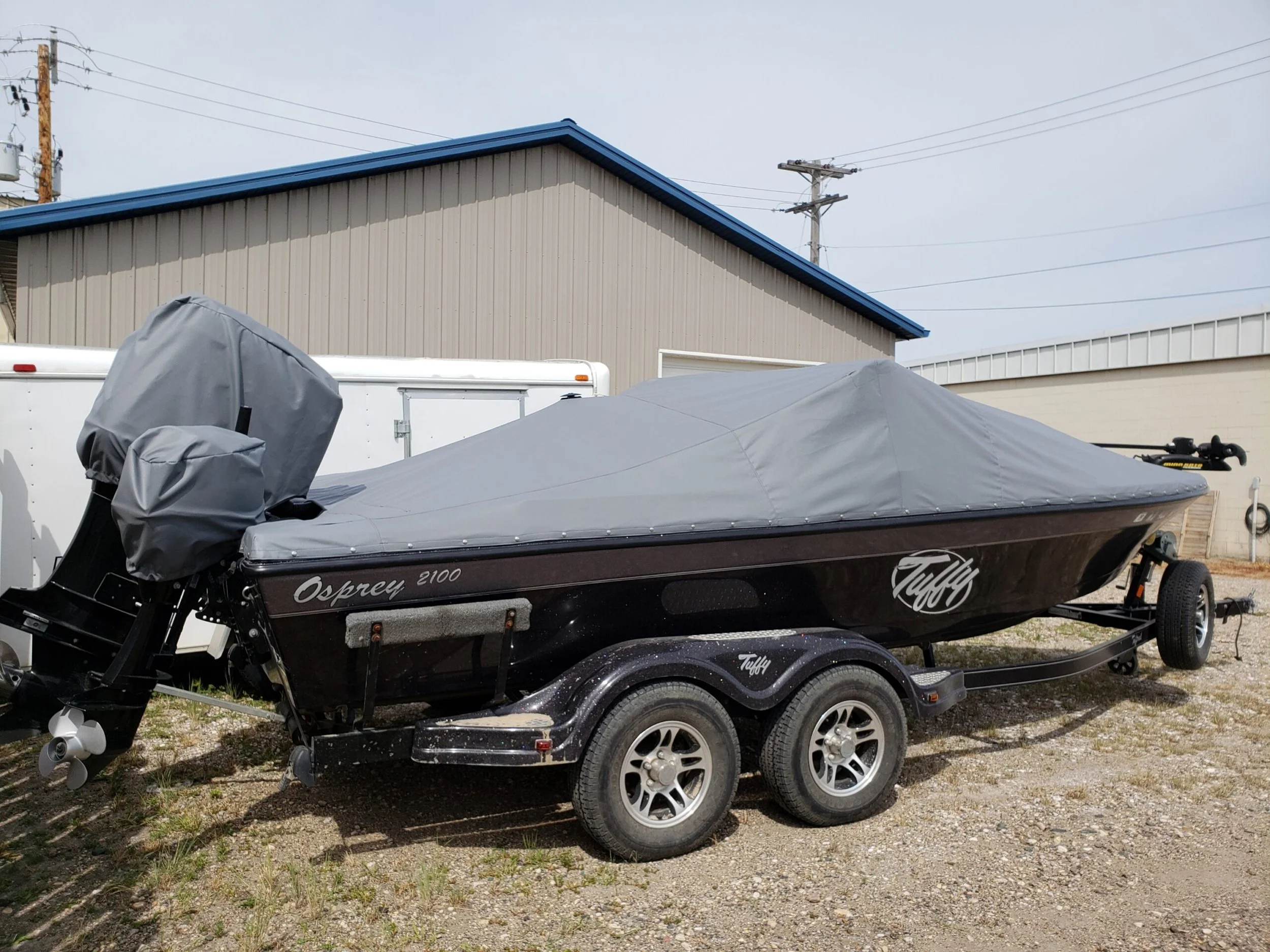 A black boat on a trailer with a custom gray boat cover