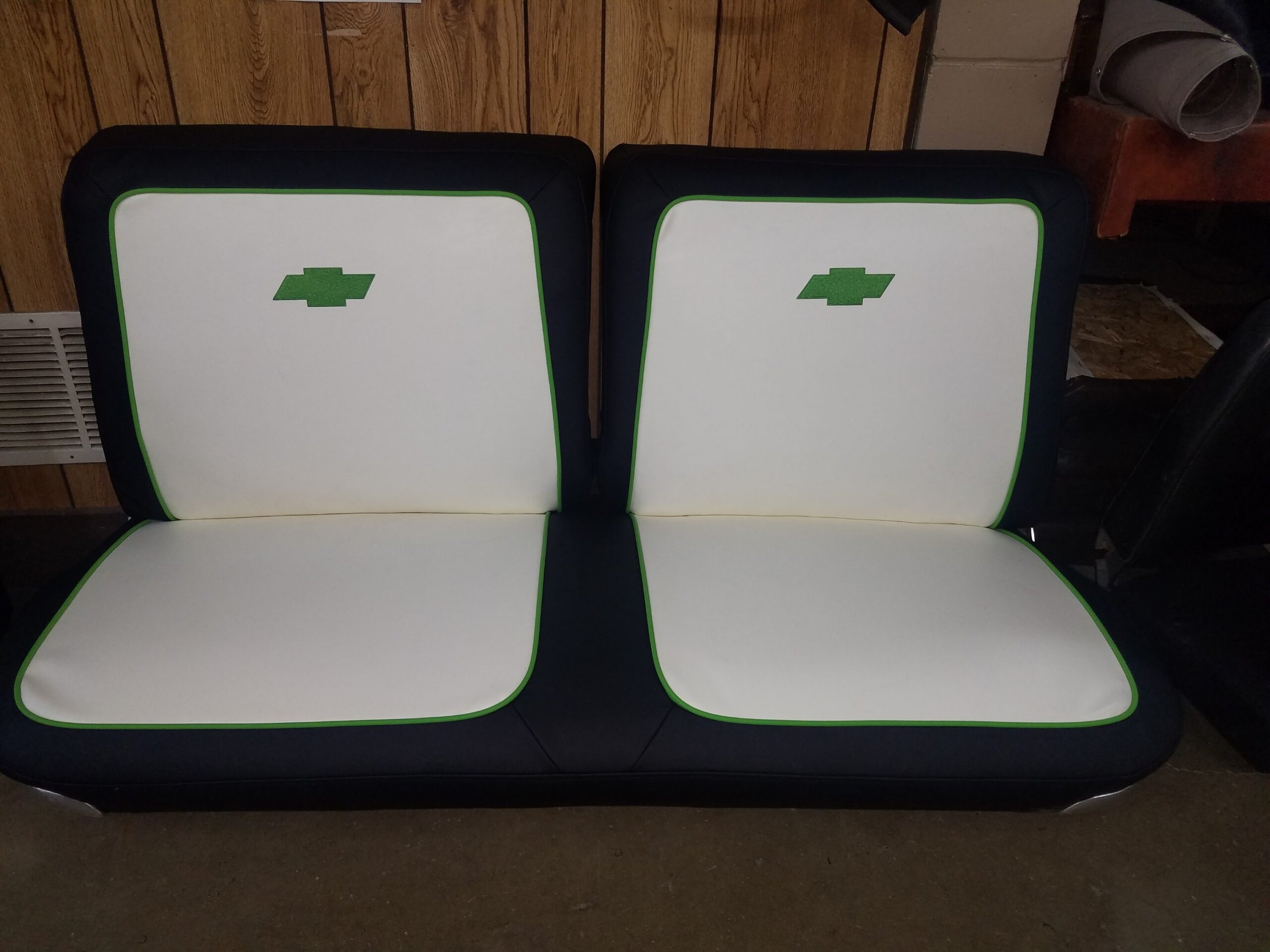 White and black bench seat with green Chevrolet logos on the backrest.