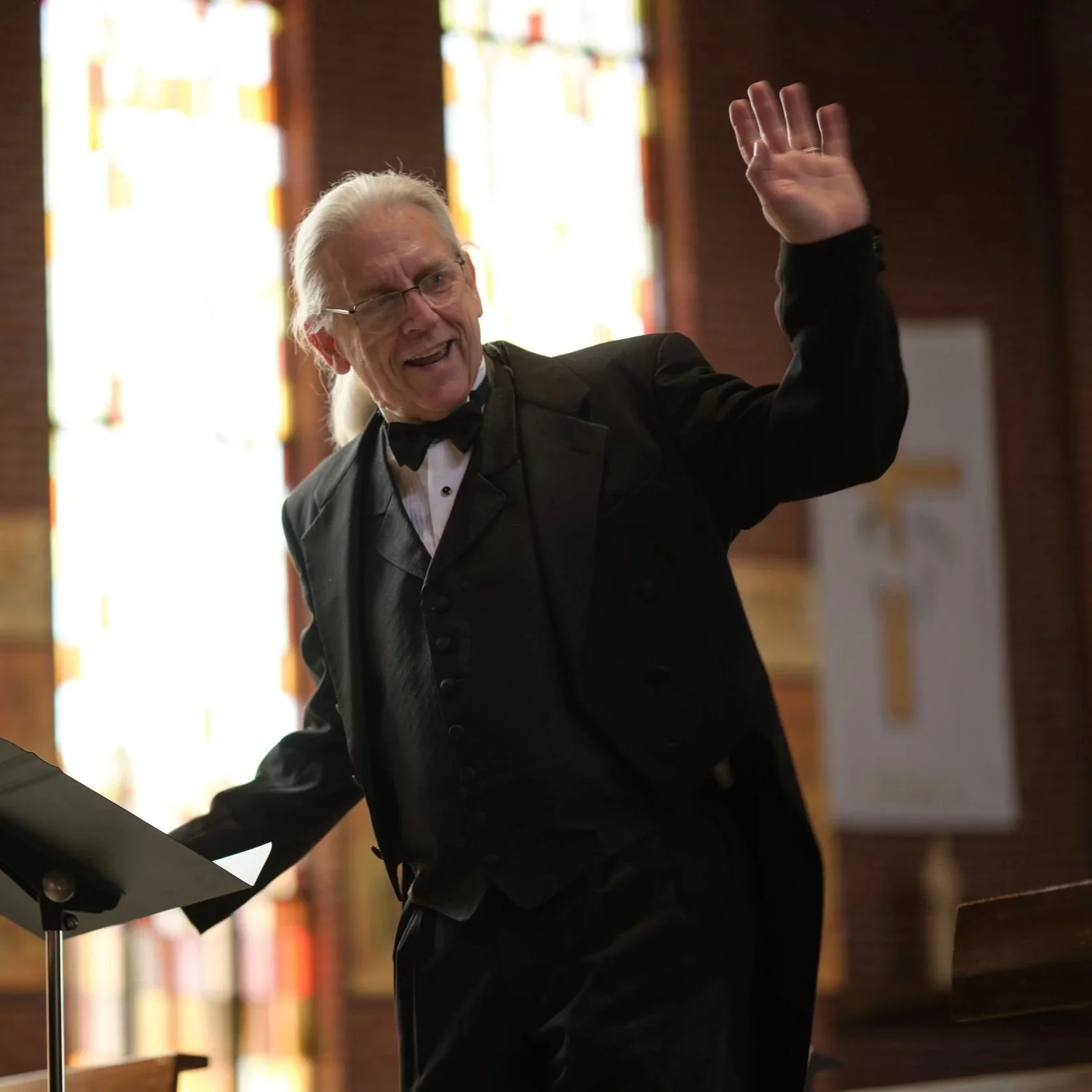 Director Steven Hoifeldt, dressed in formal attire, including a tuxedo and bow tie. He is smiling and waving with his left hand.