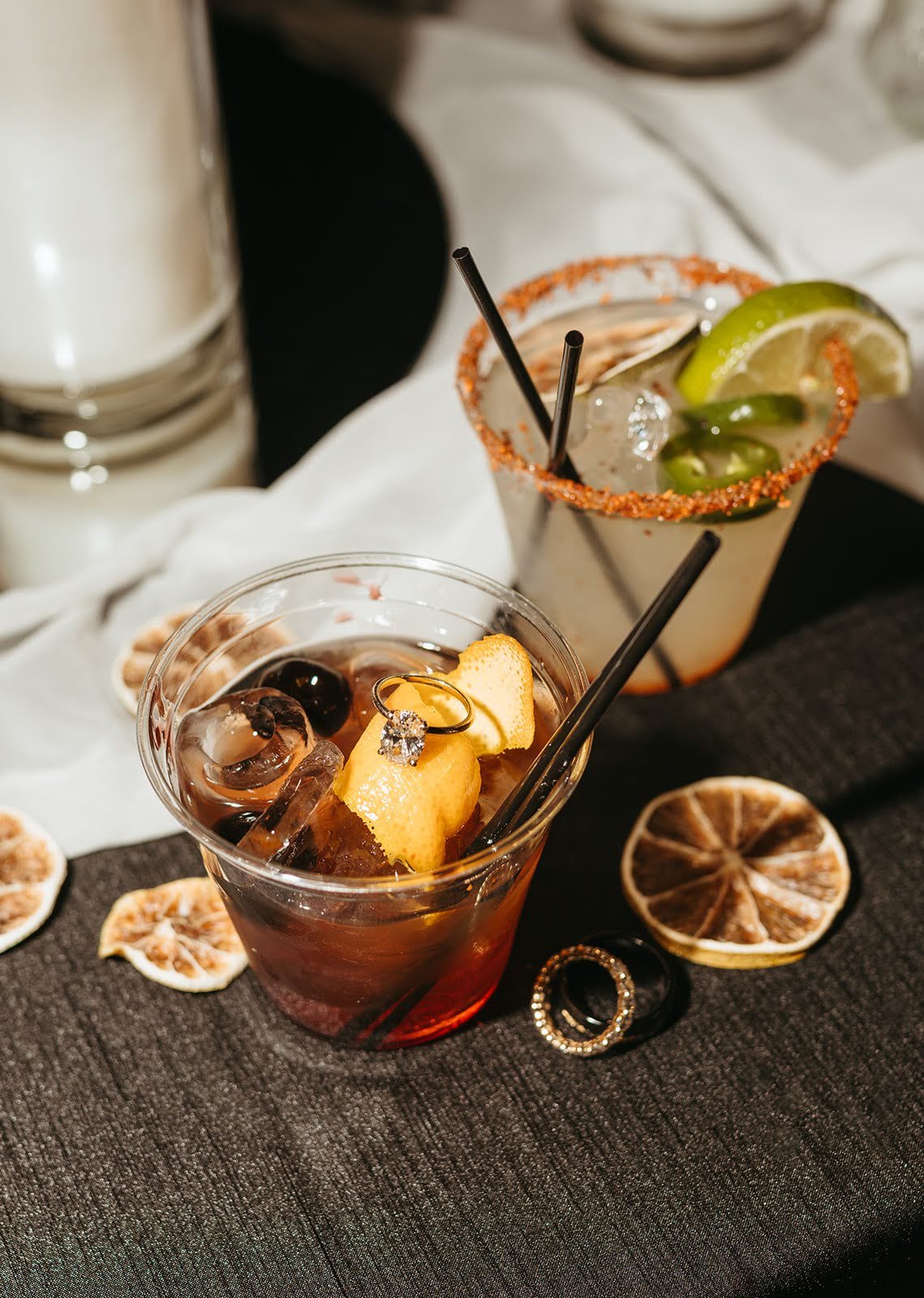 two signature cocktails, an old fashioned and a spicy margarita, with the engagement ring in the drink