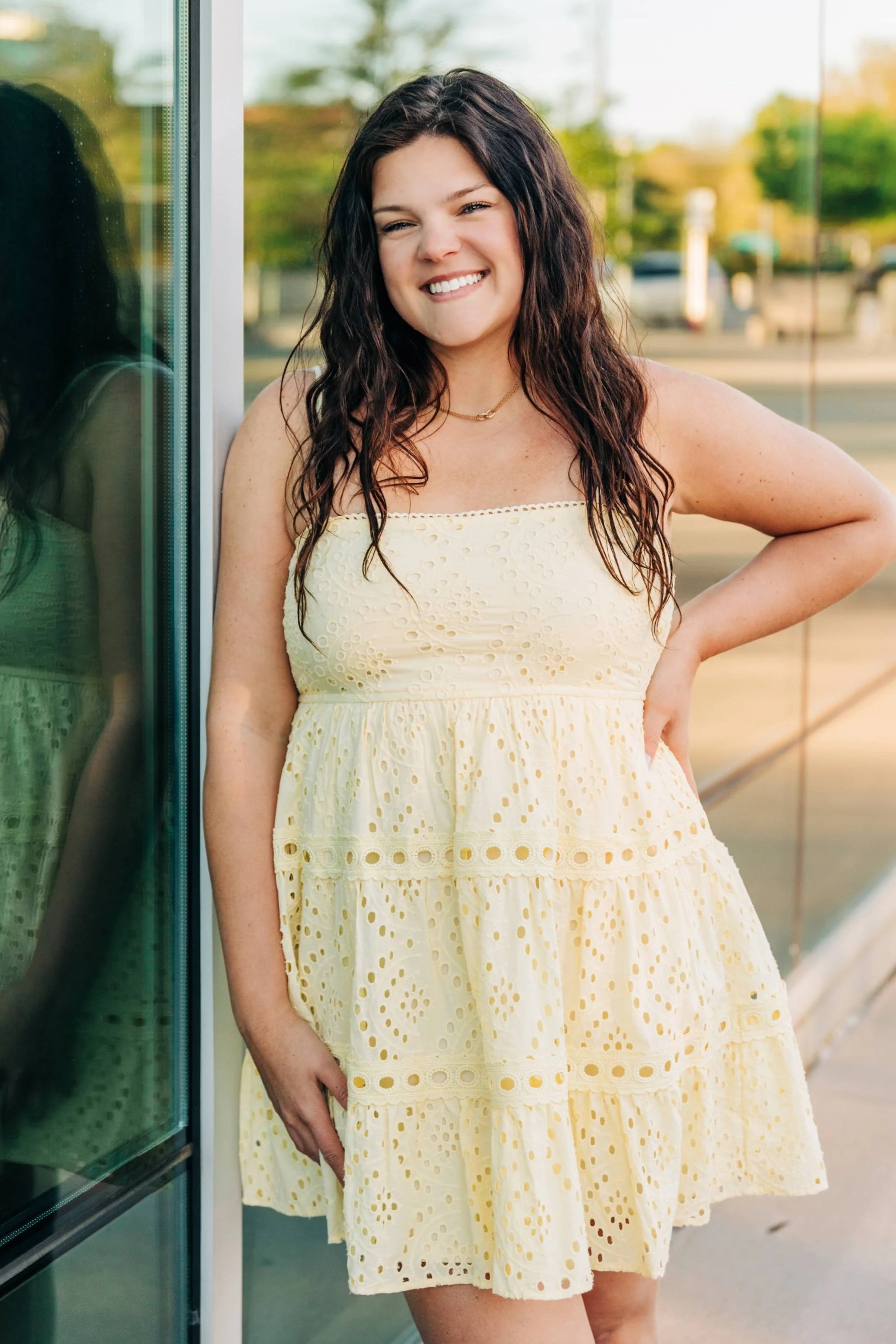 Meet Kenzie - yellow dress leaning against the wall with hand on hip