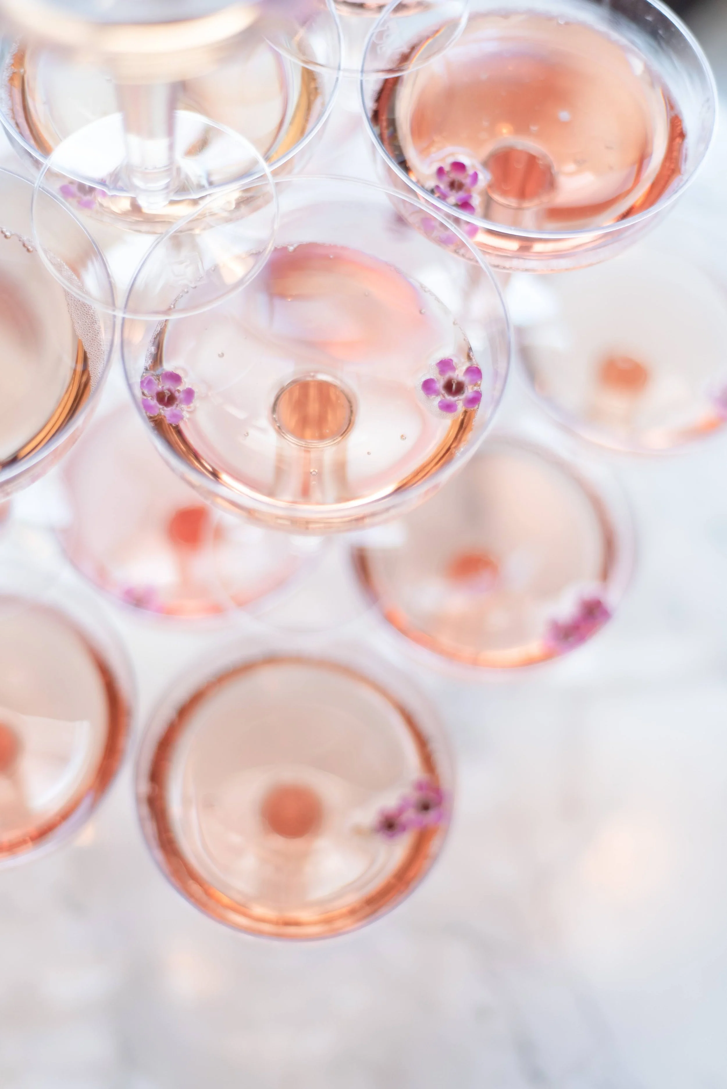 close up of champagne glasses in a champagne tower with rose prosecco and tiny edible flowers