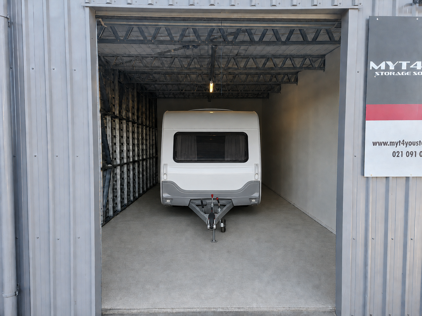 Compact caravan parked inside a drive-up storage unit at Myt4you Storage Ravenswood near Christchurch