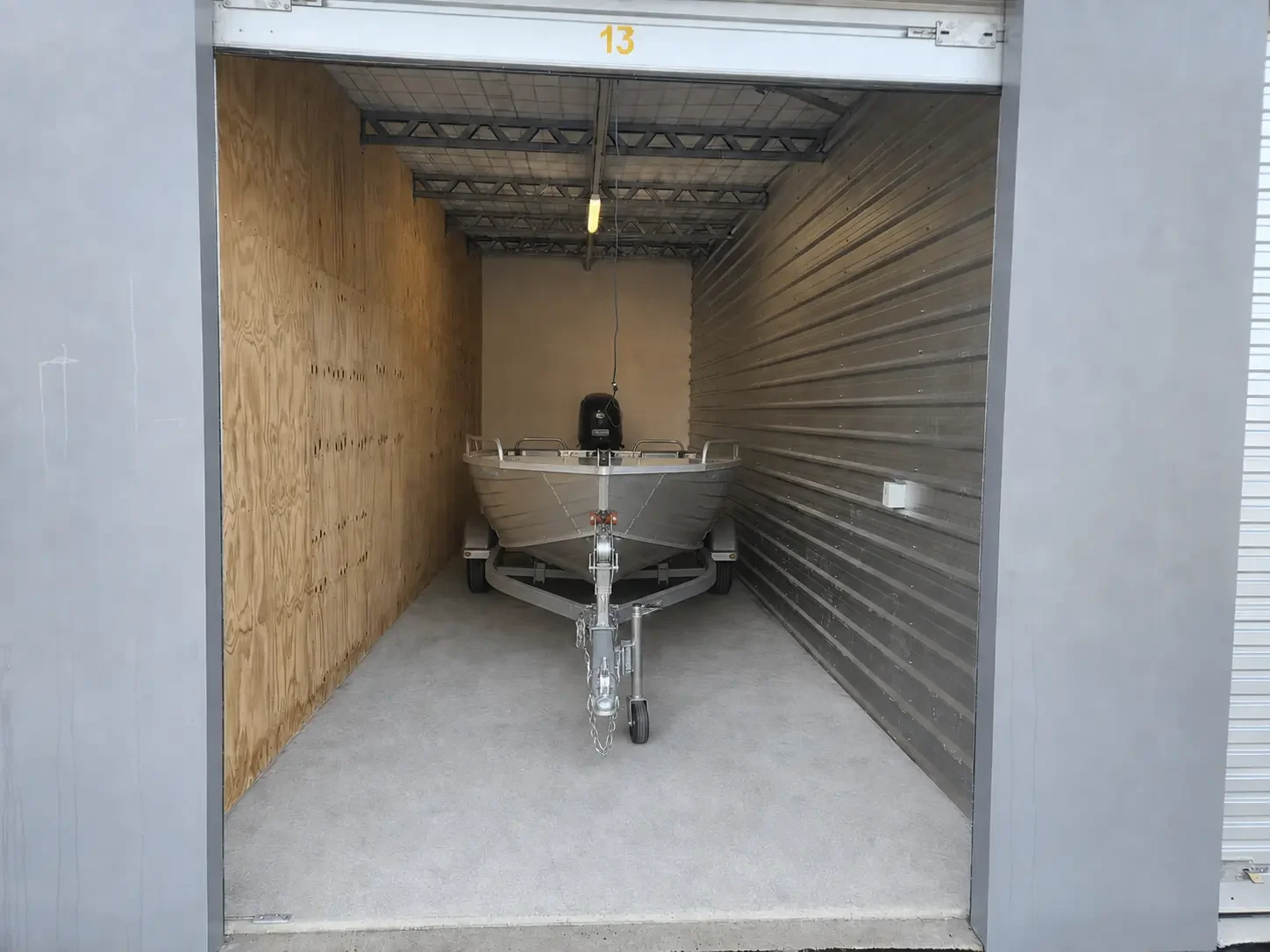 Compact trailer boat stored inside a drive-up unit at Myt4you Storage Ravenswood