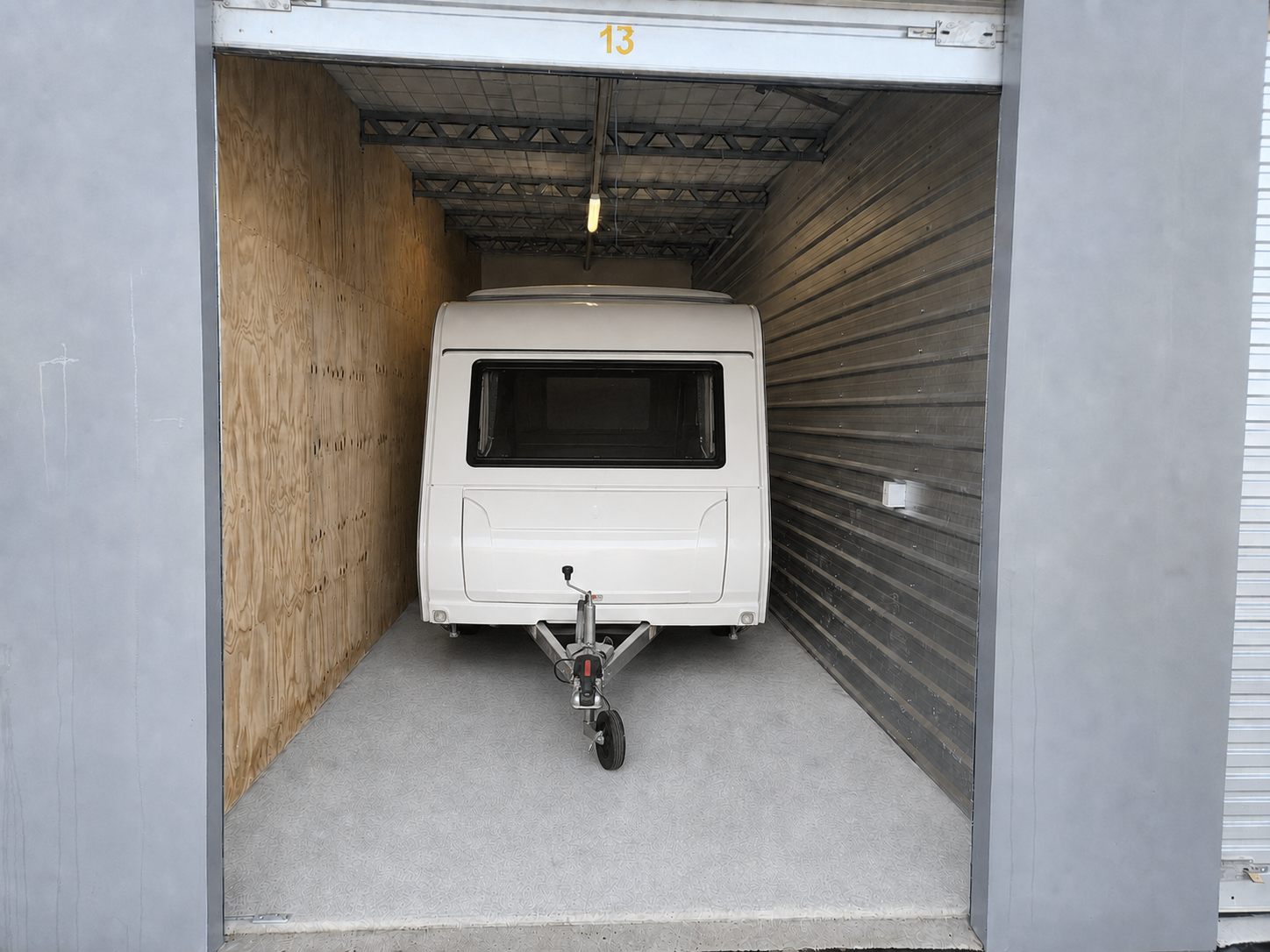 Compact touring caravan with tow bar facing the entrance inside an enclosed unit at Myt4you Storage Ravenswood