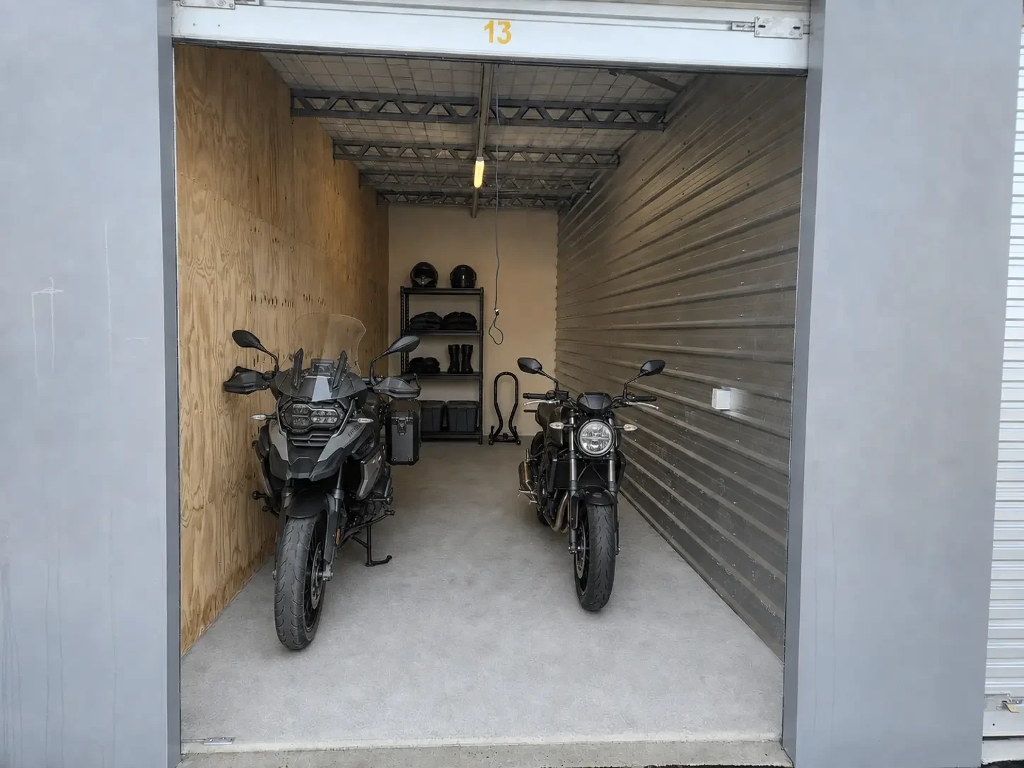 Two motorbikes with helmets and riding gear inside an enclosed storage unit at Myt4you Storage Ravenswood