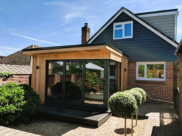 Bespoke home extension constructed using Structural Insulated Panels with bifold doors and vertical wooden cladding.