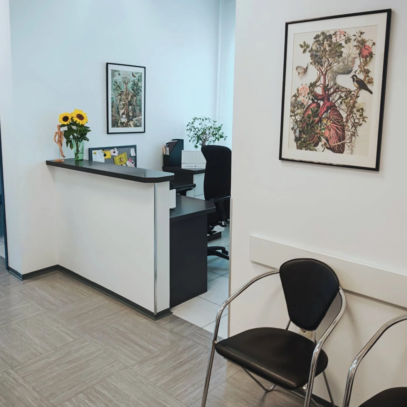 Wartezimmer mit Stühlen, einem Schreibtisch, Pflanzen und Wandbildern in einem medizinischen oder Bürogebäude