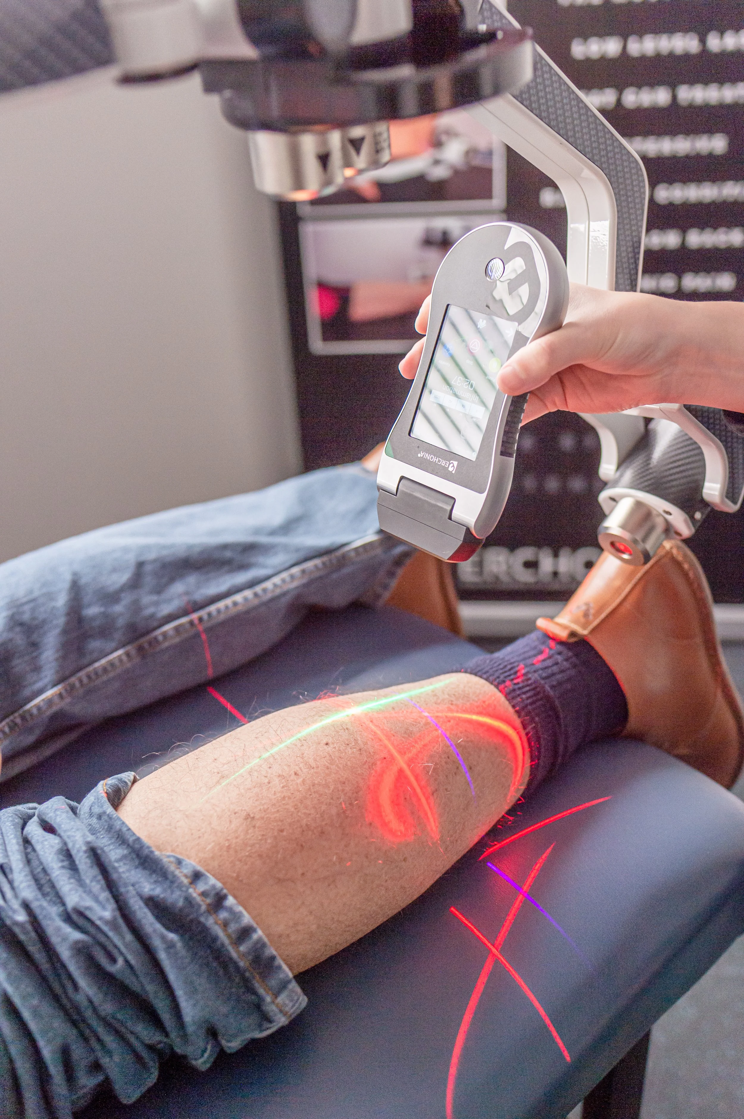 A person undergoing laser treatment on their leg, with the technician holding a handheld low-level laser device. 