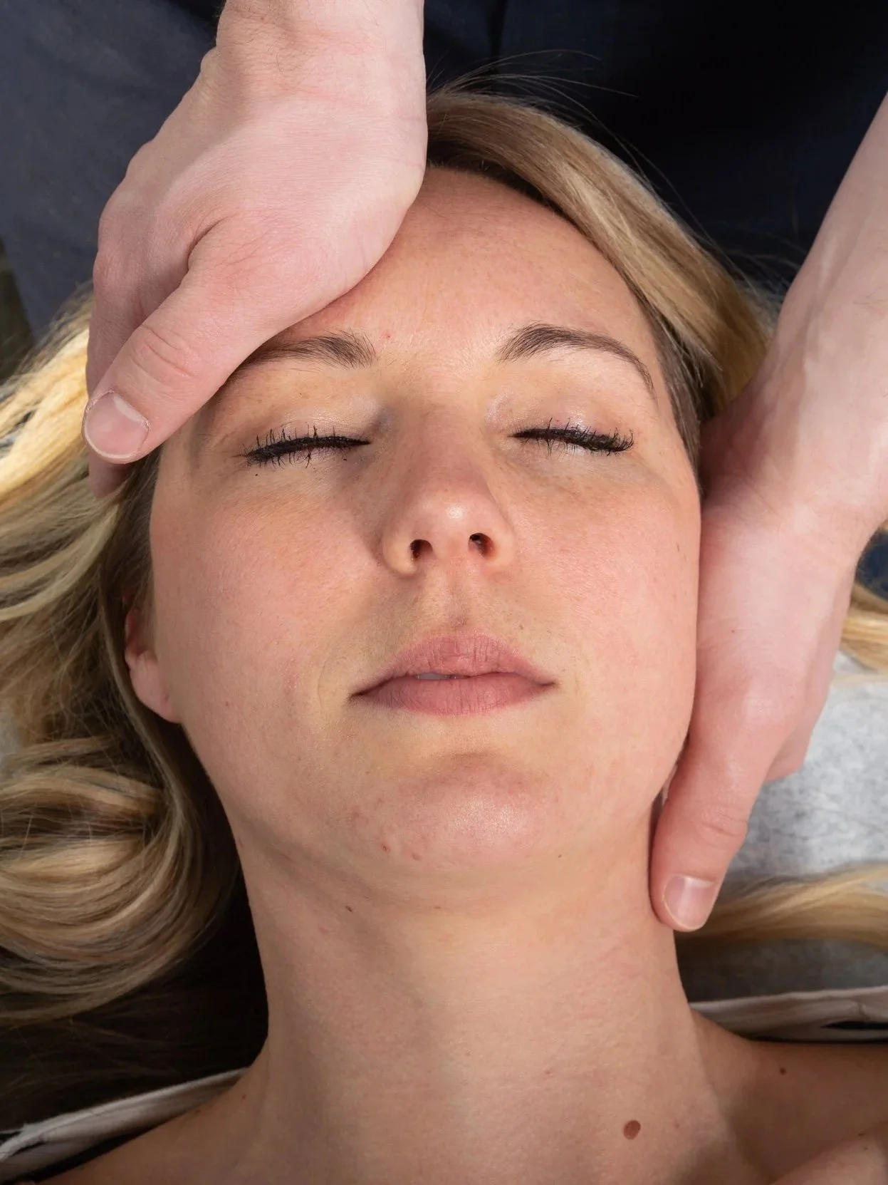 A patient looking relaxed while receiving cranial adjustments at ICE