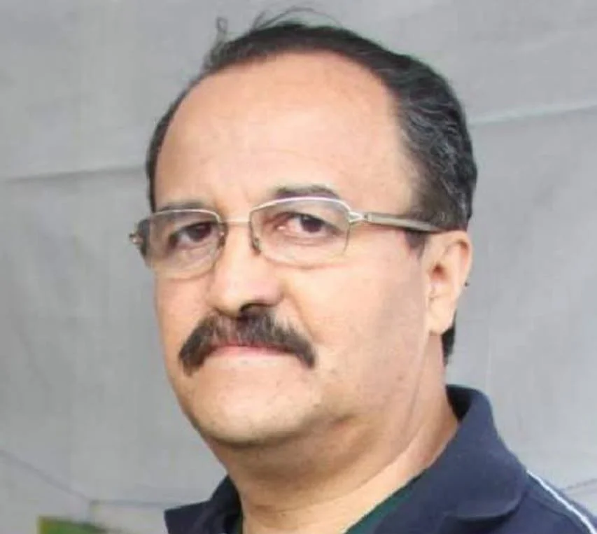 A man with glasses and a mustache looking slightly to the side.