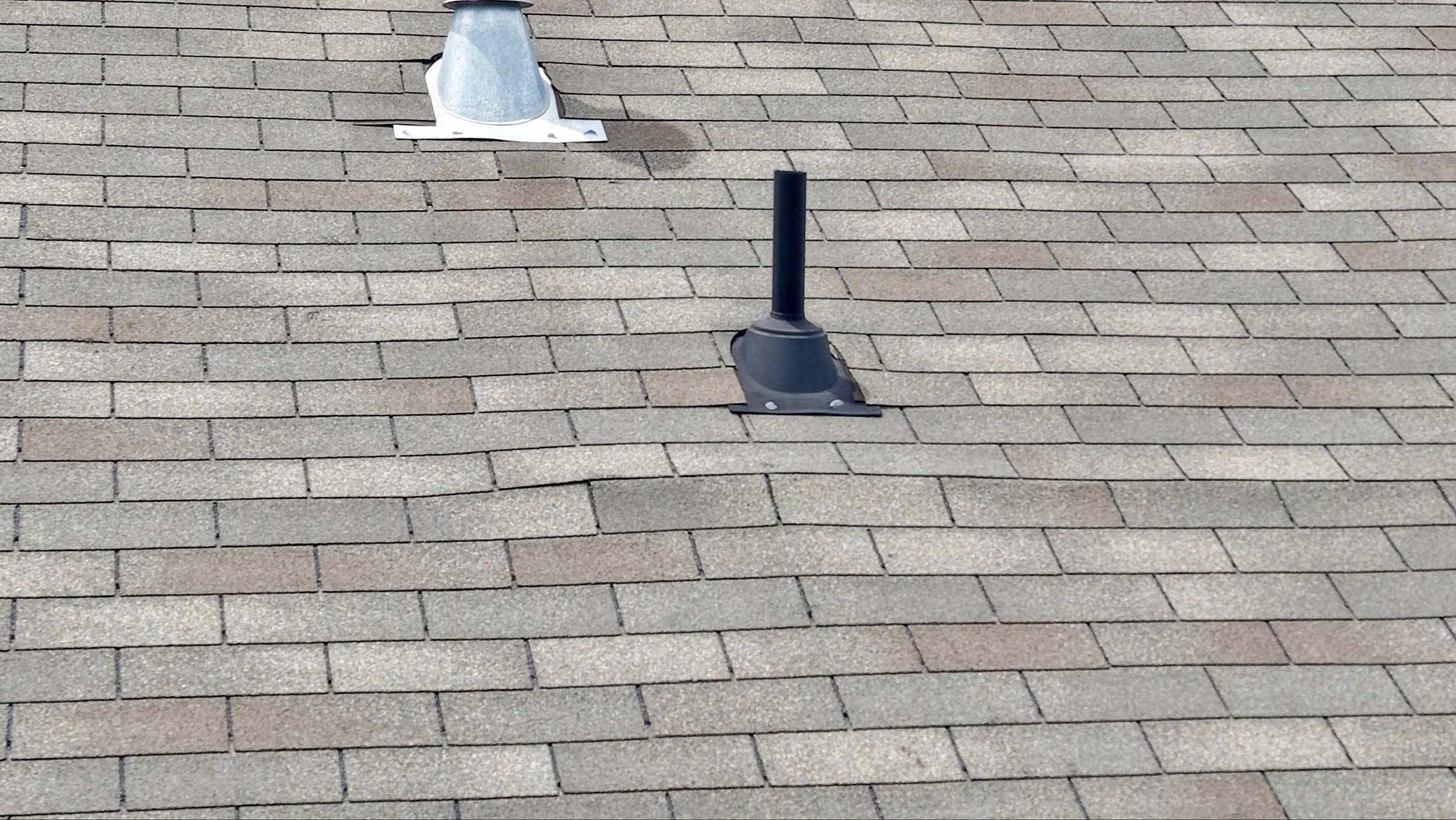 Roof with asphalt shingles, vent pipe, and a roof jack.