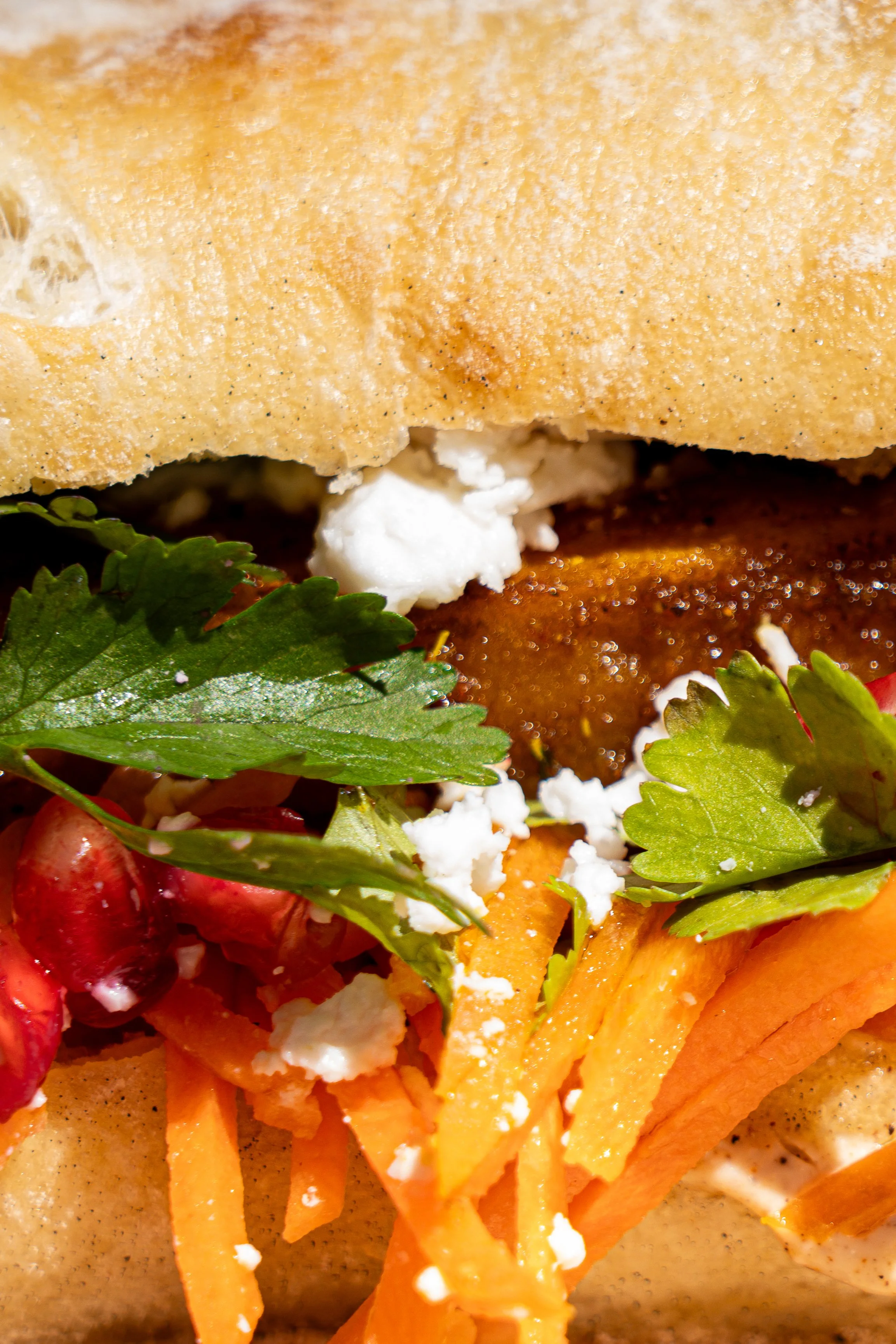 Un sandwich avec de la salade, des légumes, des herbes, feta.