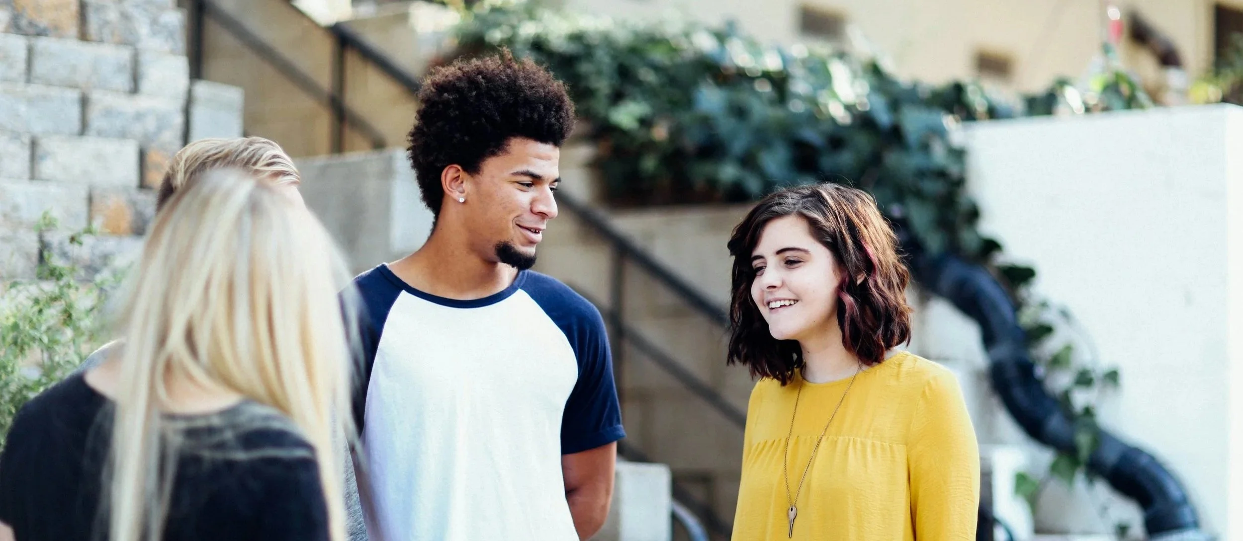 A group of four young adults talking and smiling outdoors at an alpha gathering