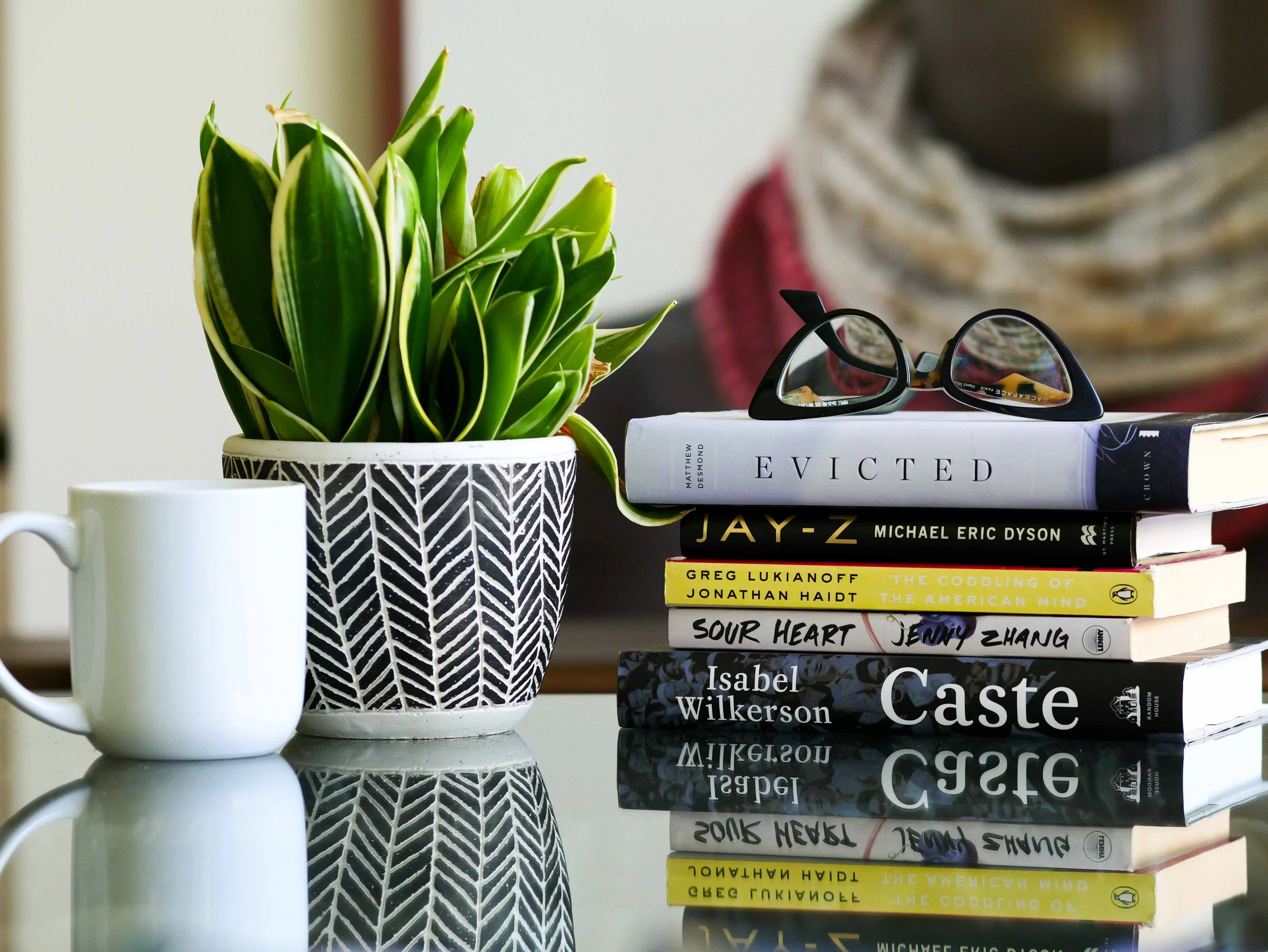 stack of books on Claudia's desk: "Evicted," "Jay-Z," "The cooking of the American mind," "Sour Heart," and "Caste."