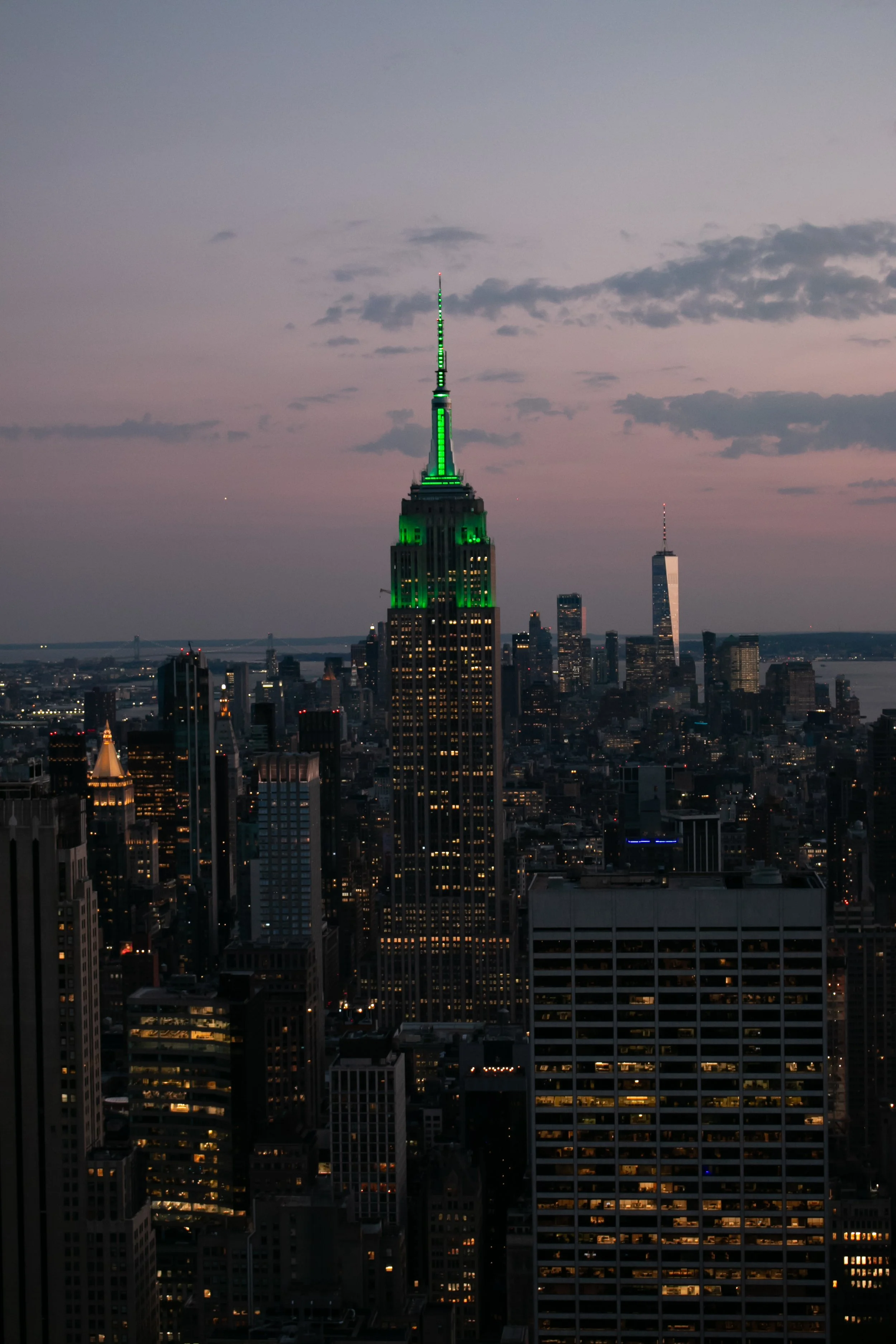 Photo of the Empire State Building at sunset in New York City after the building has illuminated the top sections with green lights