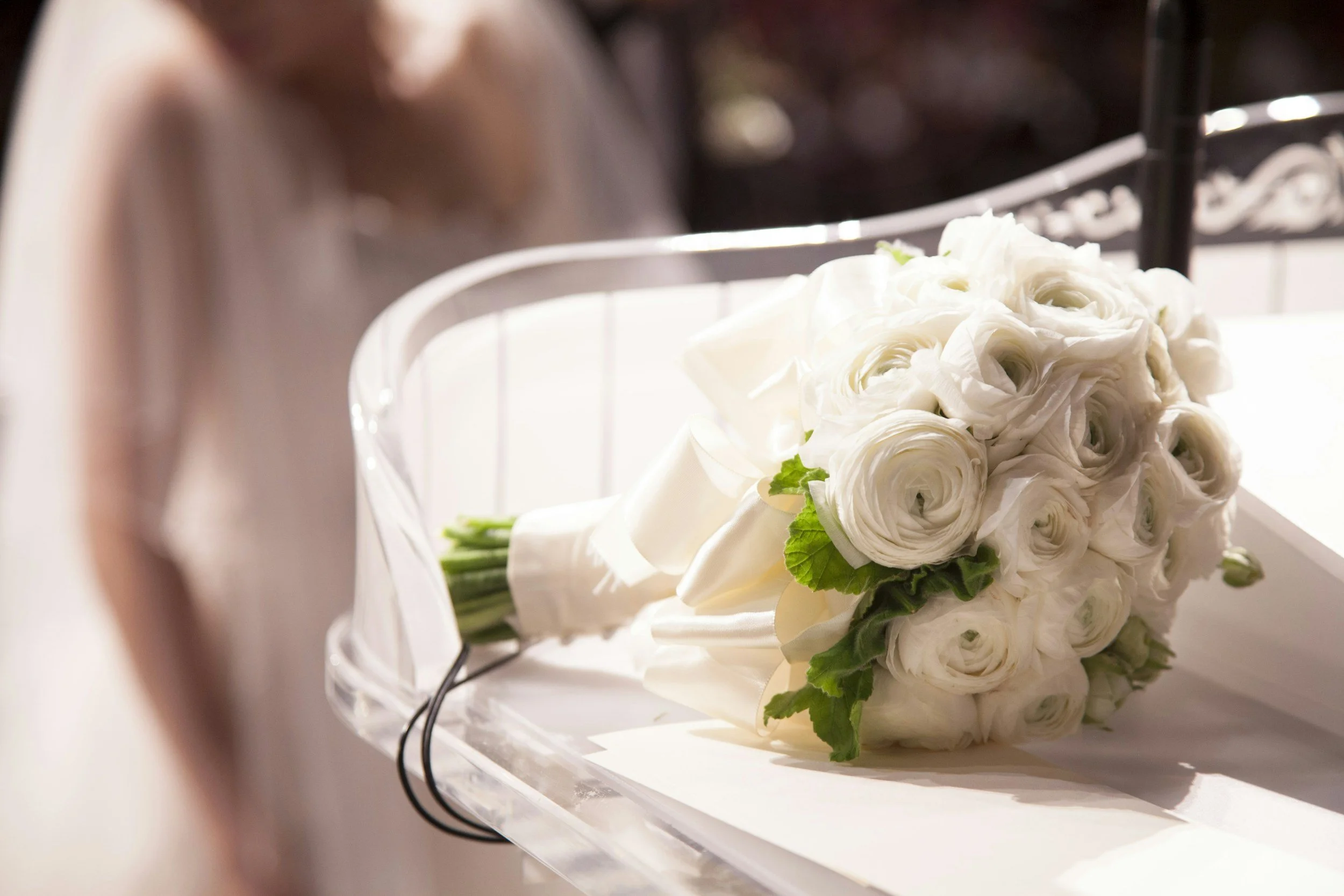 A bouquet of white roses with green leaves resting on a white surface.