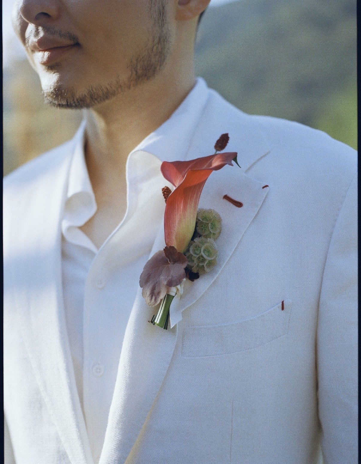 Close-up of a man in a white suit with a floral boutonniere on his lapel.