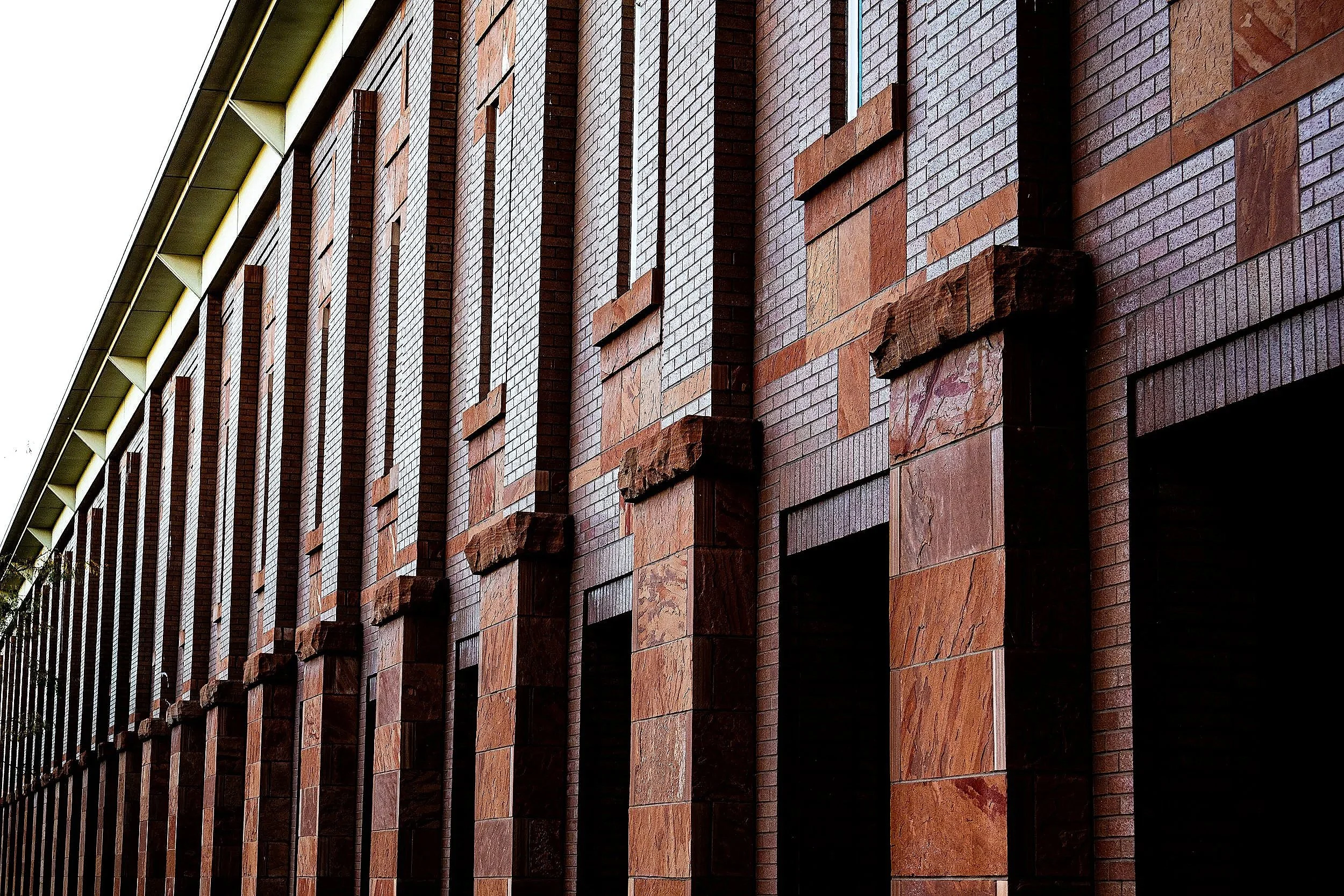 Close-up of a building's exterior wall made of brick and stone with tall, narrow windows.